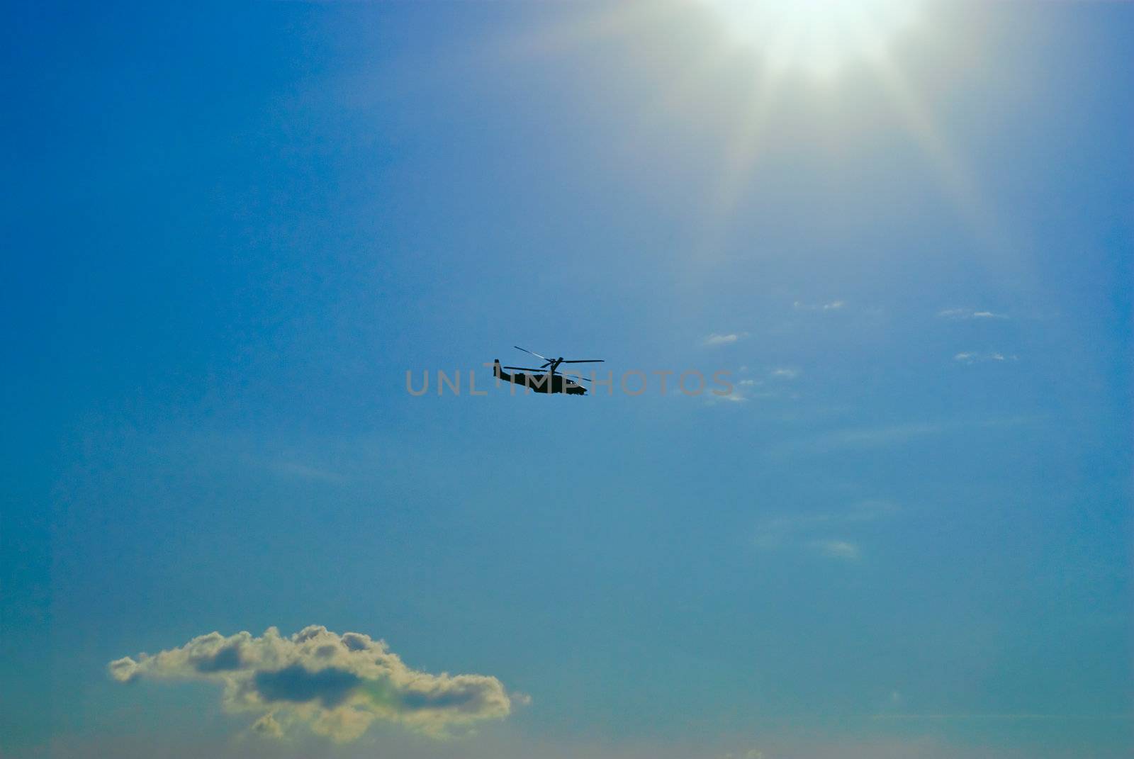 Military helicopter flying in the sky against a background of bright sunshine
