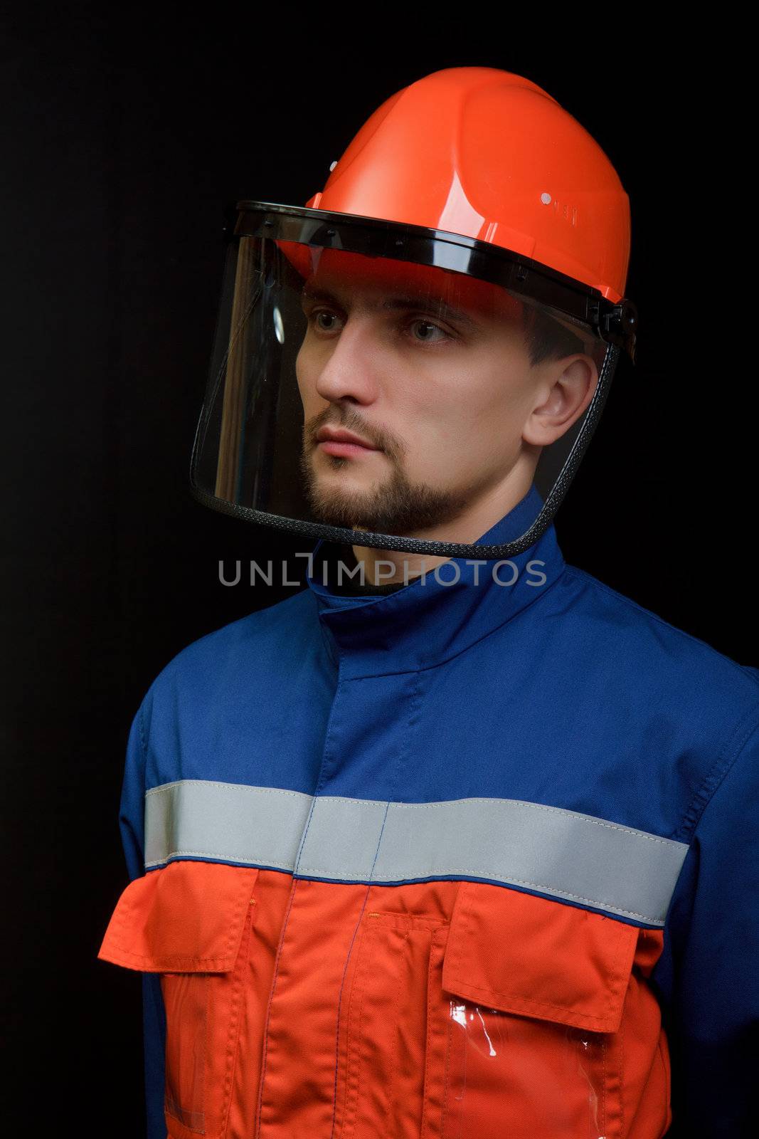 The worker in overalls and a helmet on a black background 