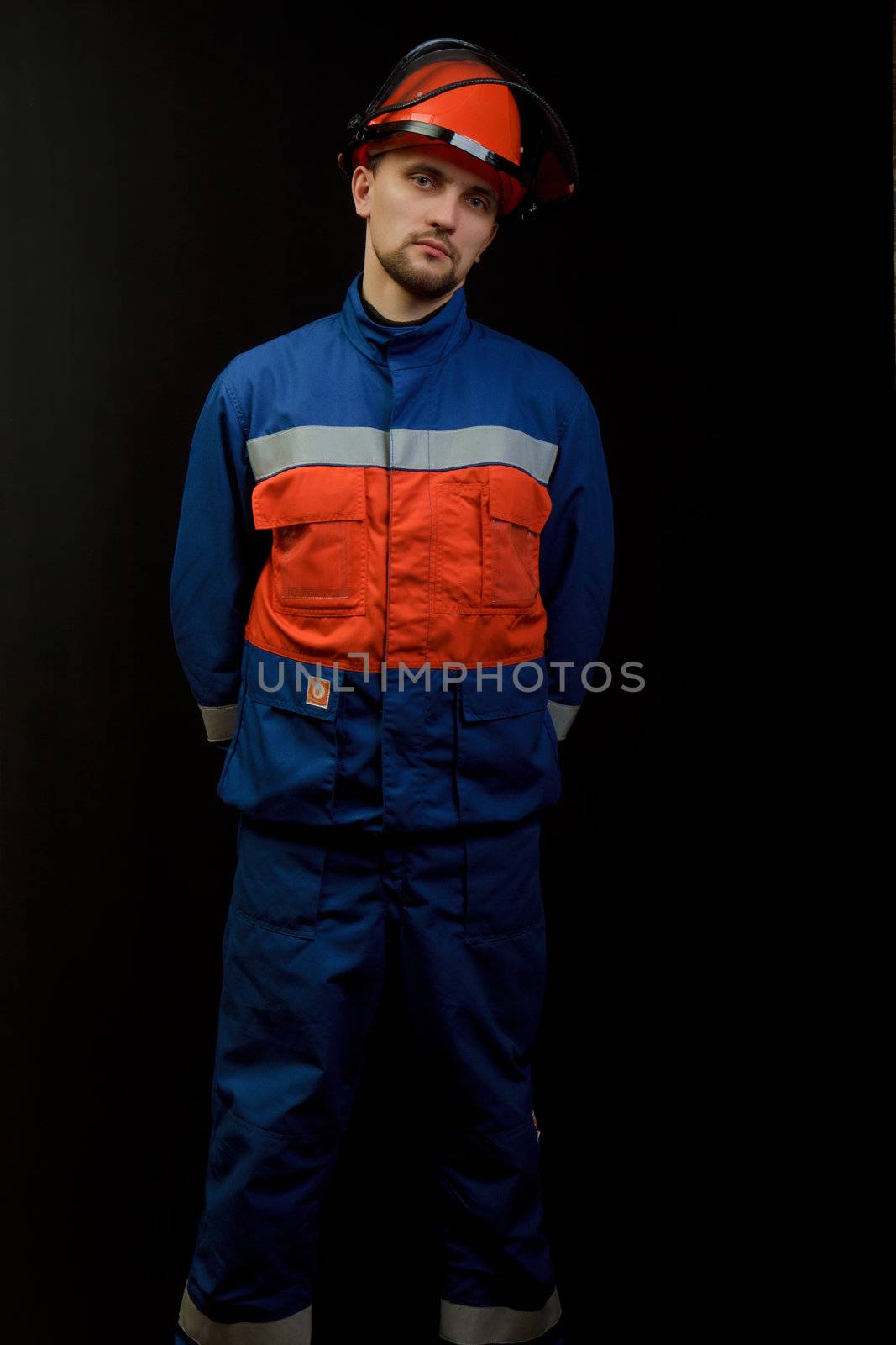 The worker in overalls and a helmet on a black background 
