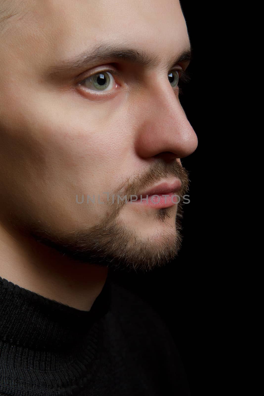 face of the young unshaven man in a black background
