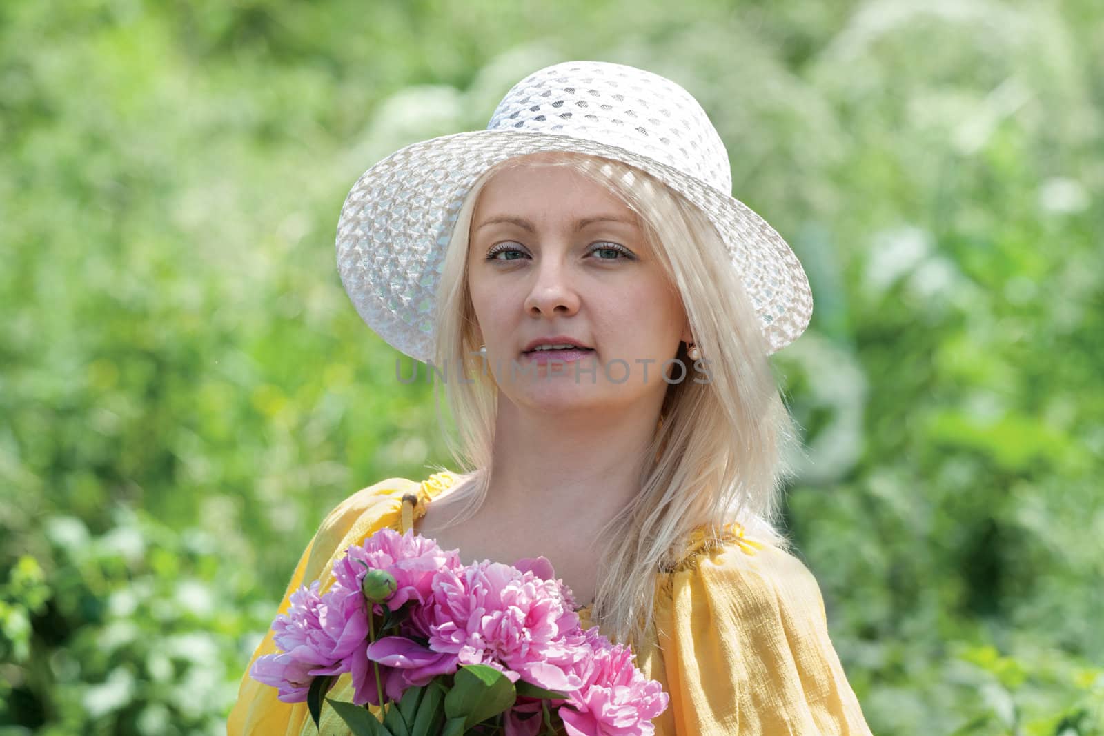 woman in a hat with flowers in the garden

