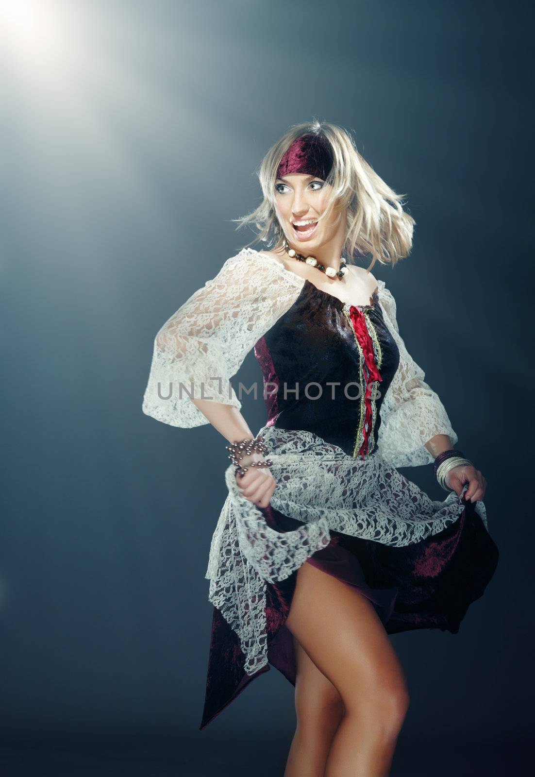 Glad lady in the Medieval pirate costume dancing indoors under the magic light