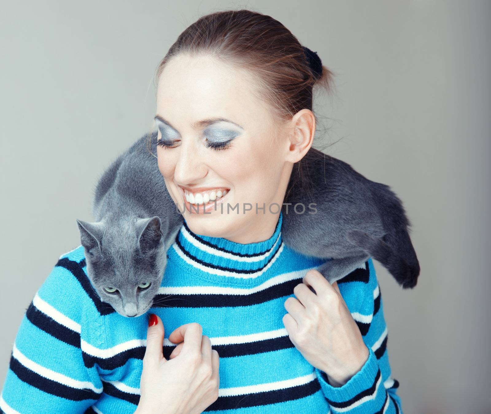 Smiling lady pampering her cat indoors. Natural light and colors