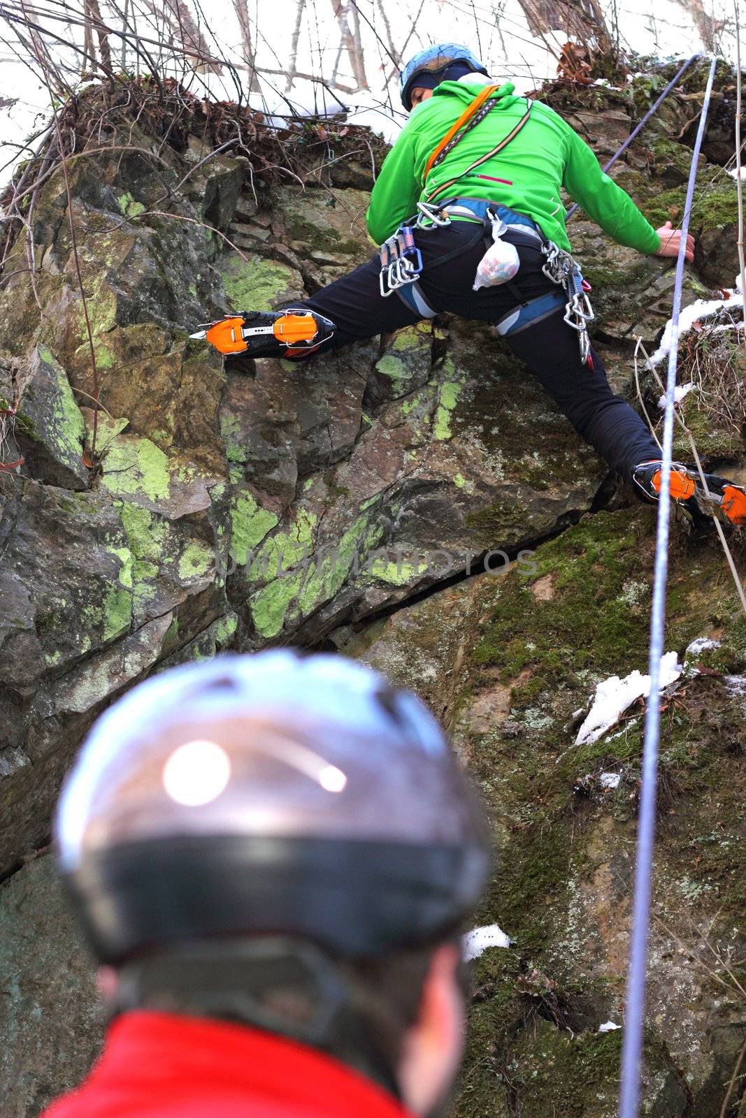 team of mountaineers climbing a rock dry face in winter