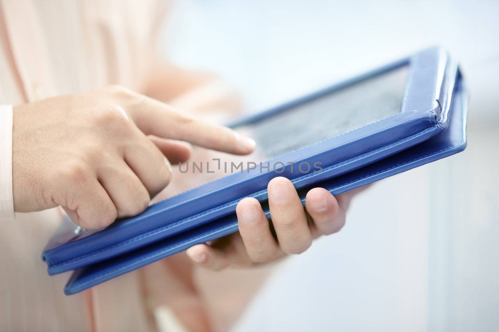 Hands of man in pink shirt using tablet PC indoors