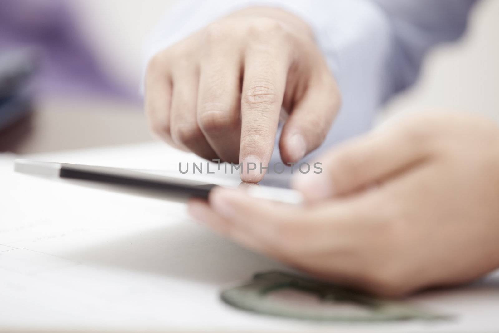 Hands of businessman using tablet PC at office