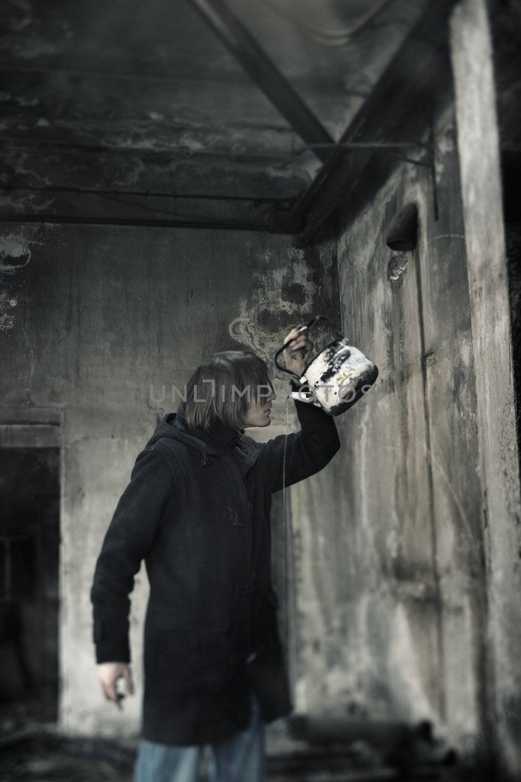 Single man indoors drinking water from the kettle in the dirty interior. Shallow depth of field due to the tilt lens for the movie effect