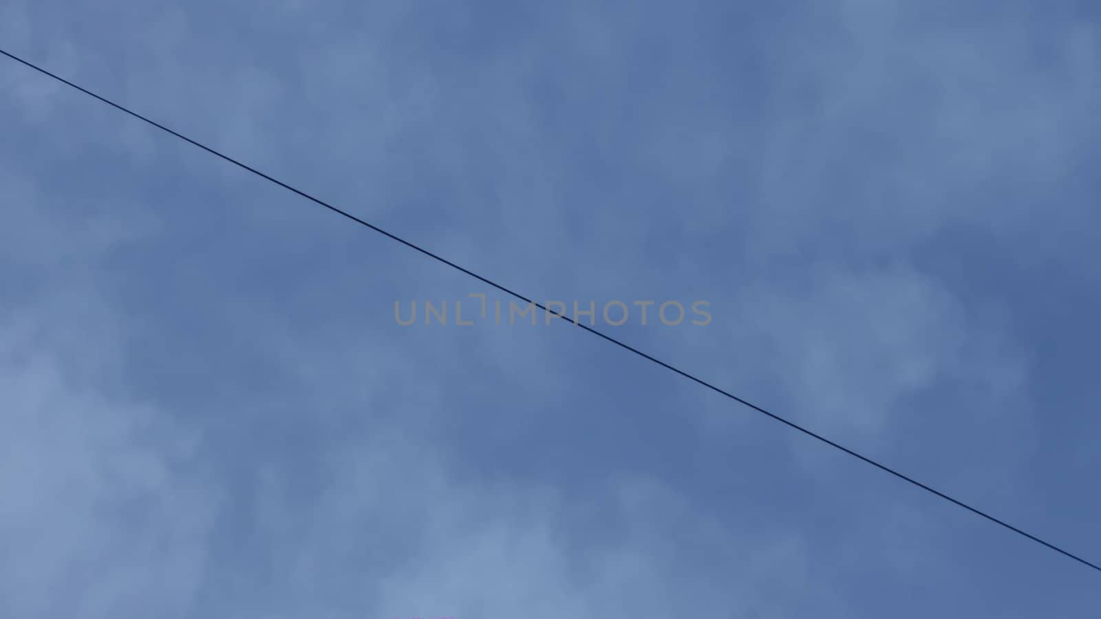 Tensioned wire in the blue evening sky with clouds