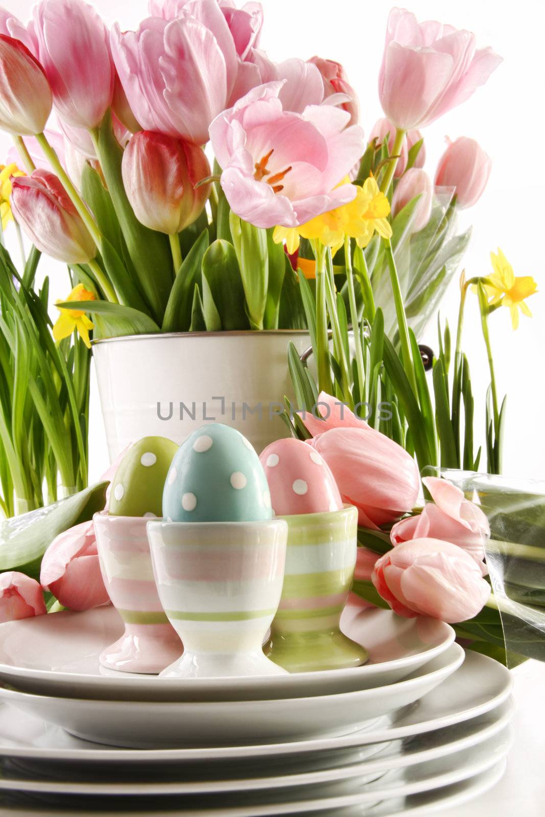 Easter eggs in cups with spring flowers on white by Sandralise