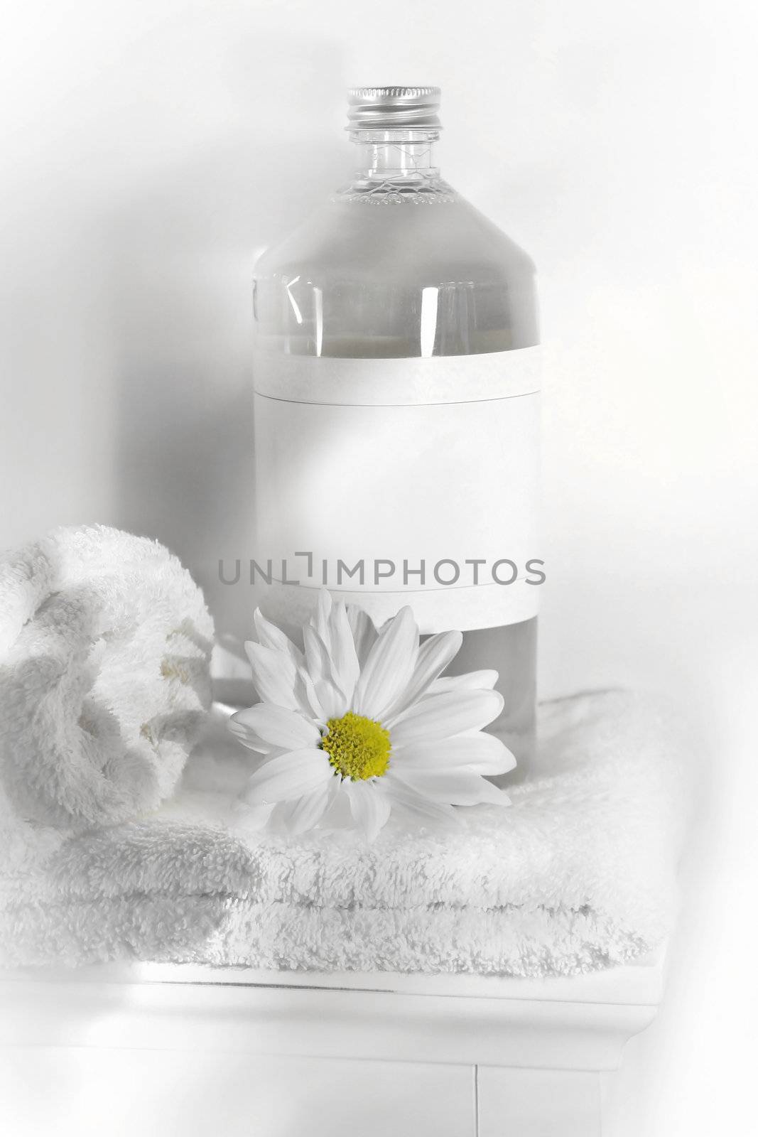 Bottle of linen water with towels and flower on cabinet