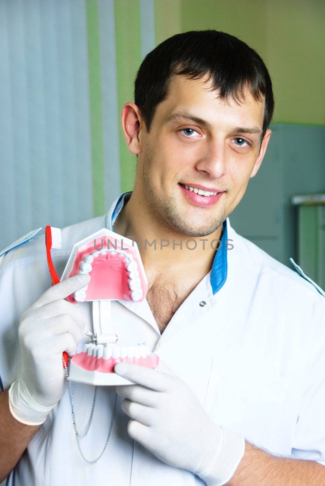 portrait of handsome young dentist teaching a patient to brush teeth