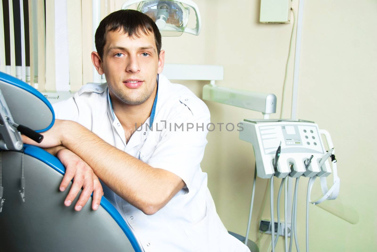portrait of a hansome young dentist sitting on the chair in the office