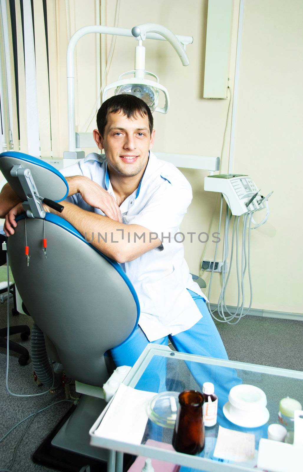 portrait of a young dentist sitting on the chair in his office