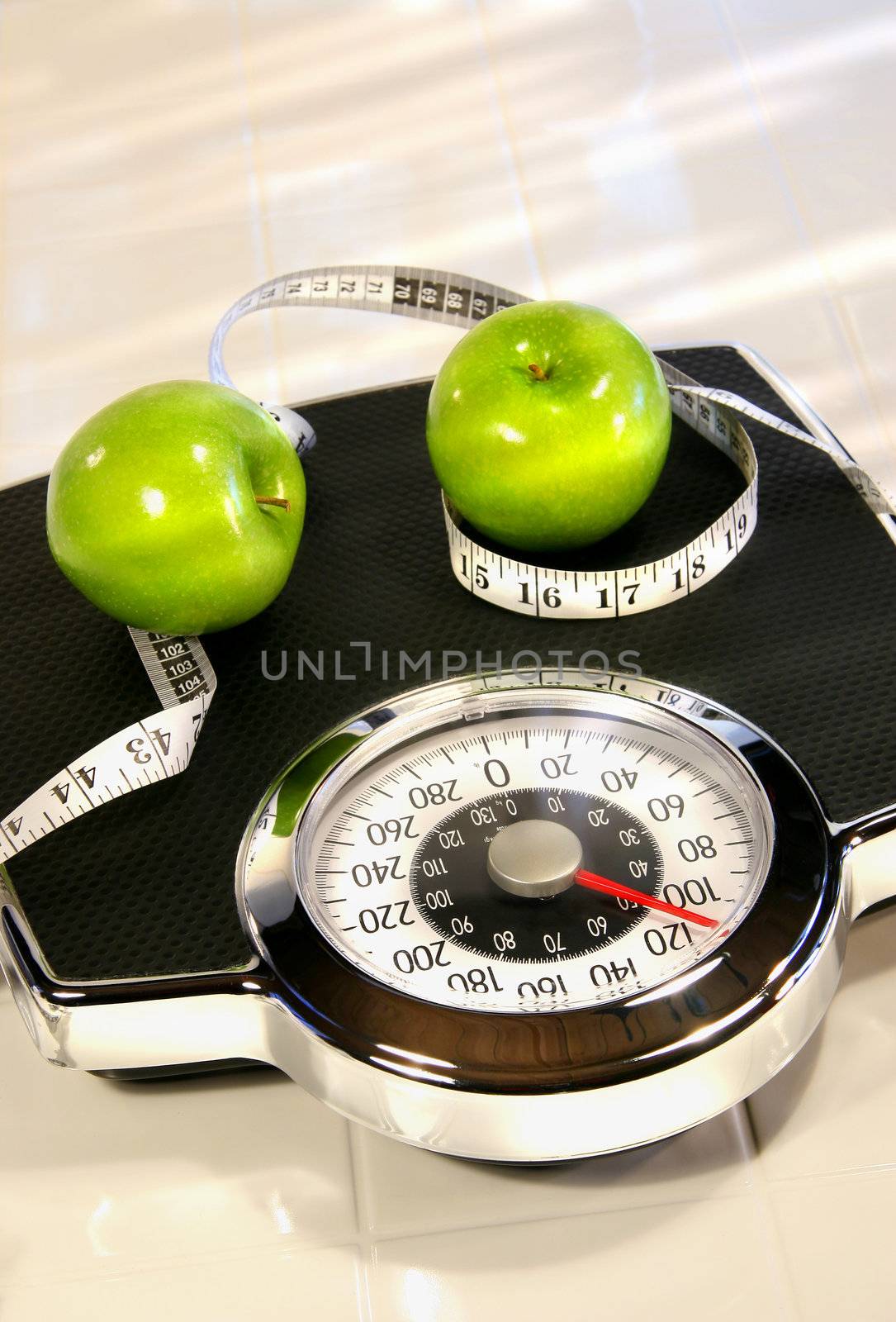 Weight scale with green apples on white tile floor