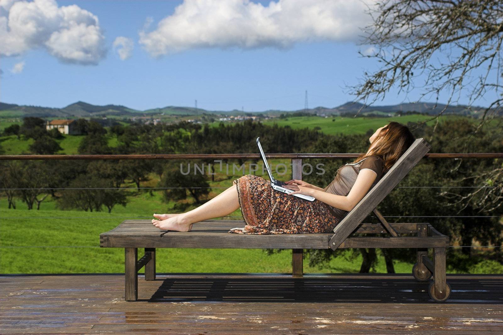 Woman enjoying a beautiful day with a laptop on her home-field