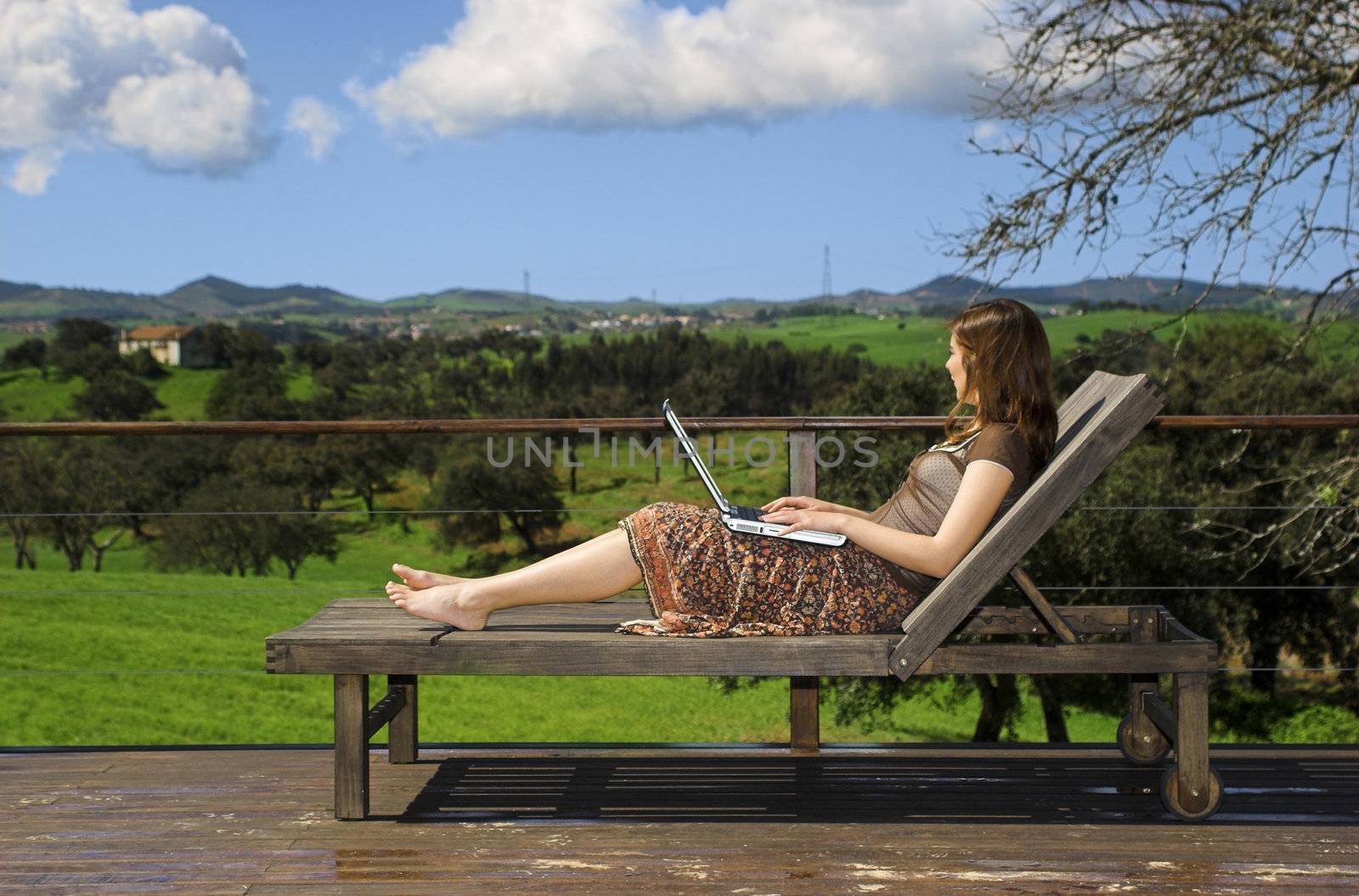 Woman enjoying a beautiful day with a laptop on her home-field