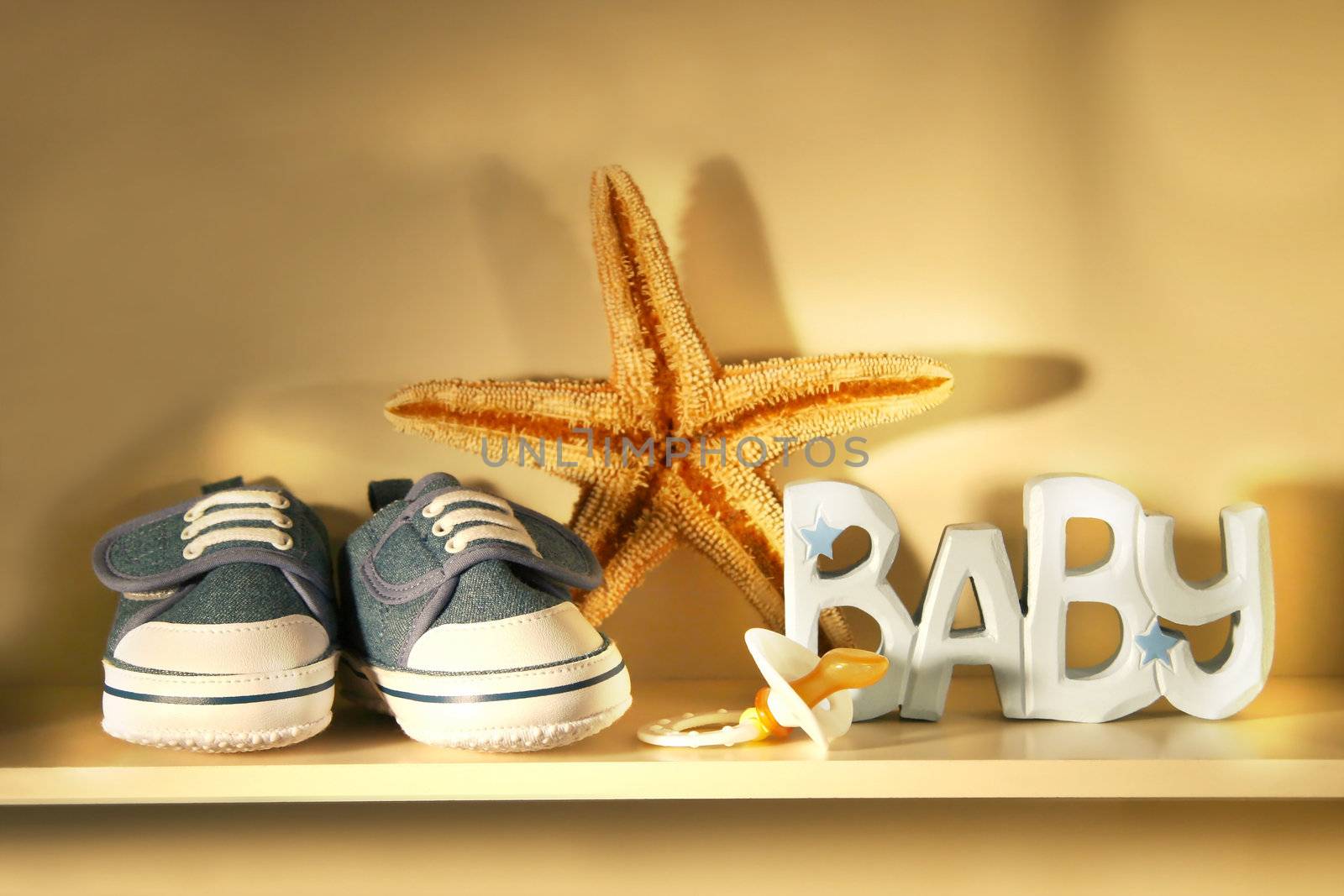 Baby shoes place on a shelf with baby pacifier, starfish etc..