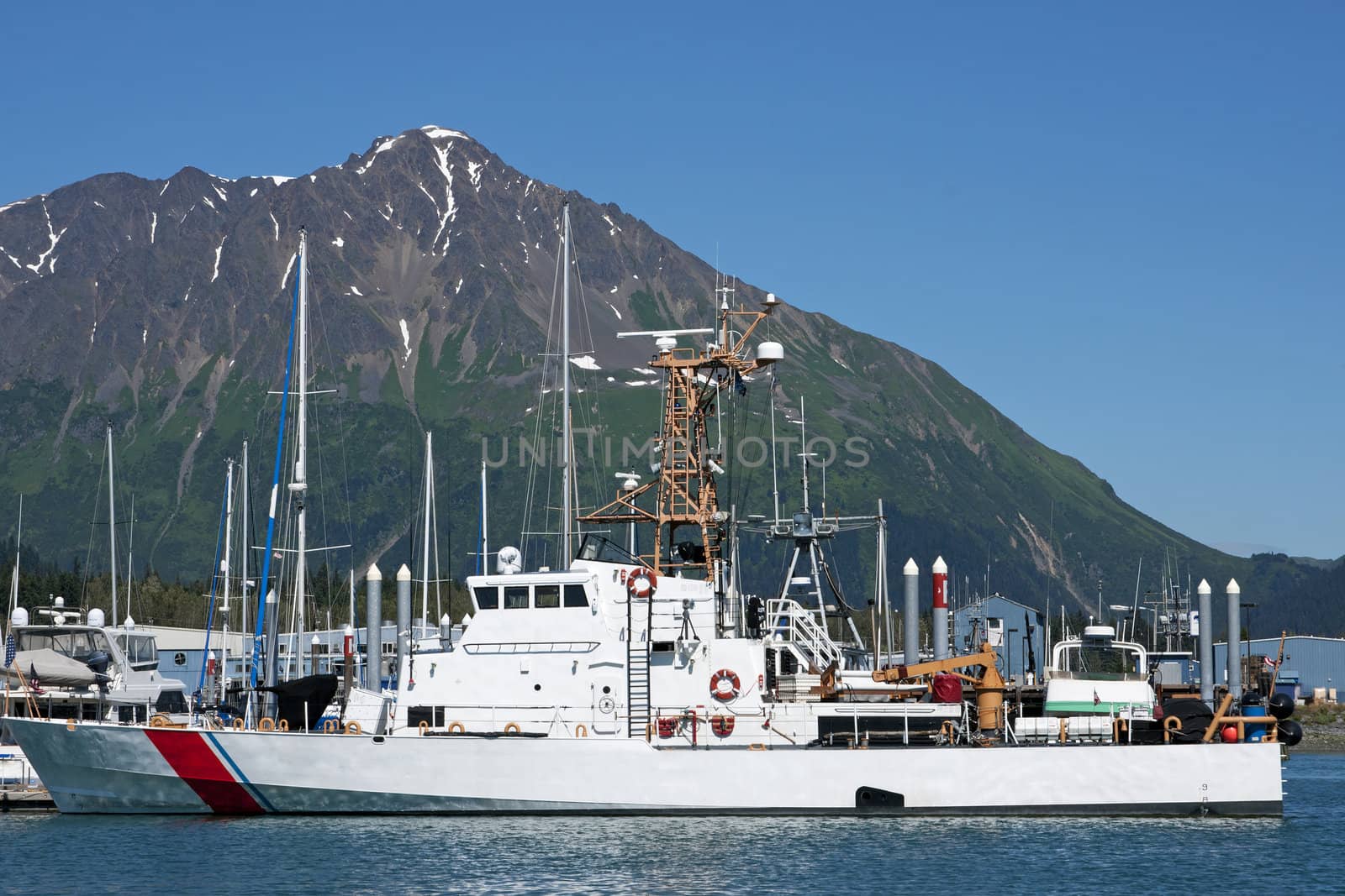 Ship in front of mountain under blue skies.