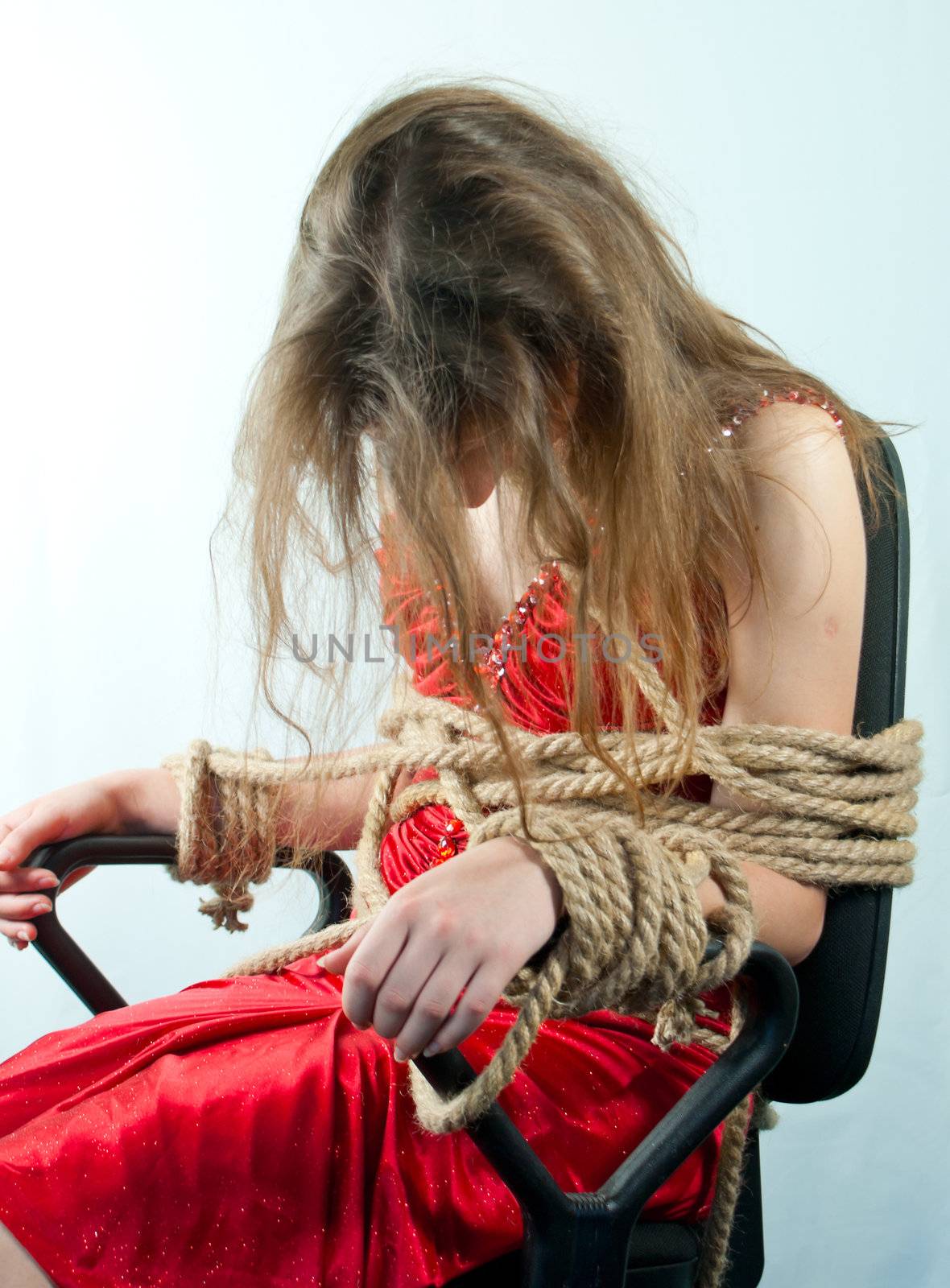 Woman tied up with a rope against light background
