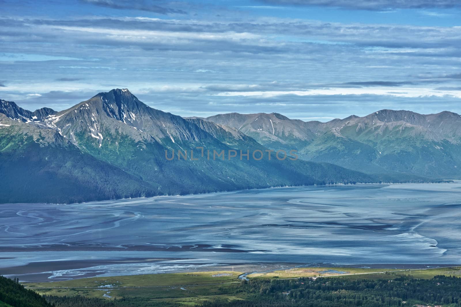 Blues is all shades cut by greens framing grey rocky mountains.