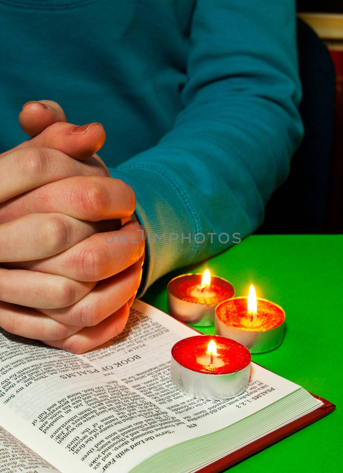 Female's arms over the Book of Psalms with burning candles. Text of Bible is the King James version which is public domain.