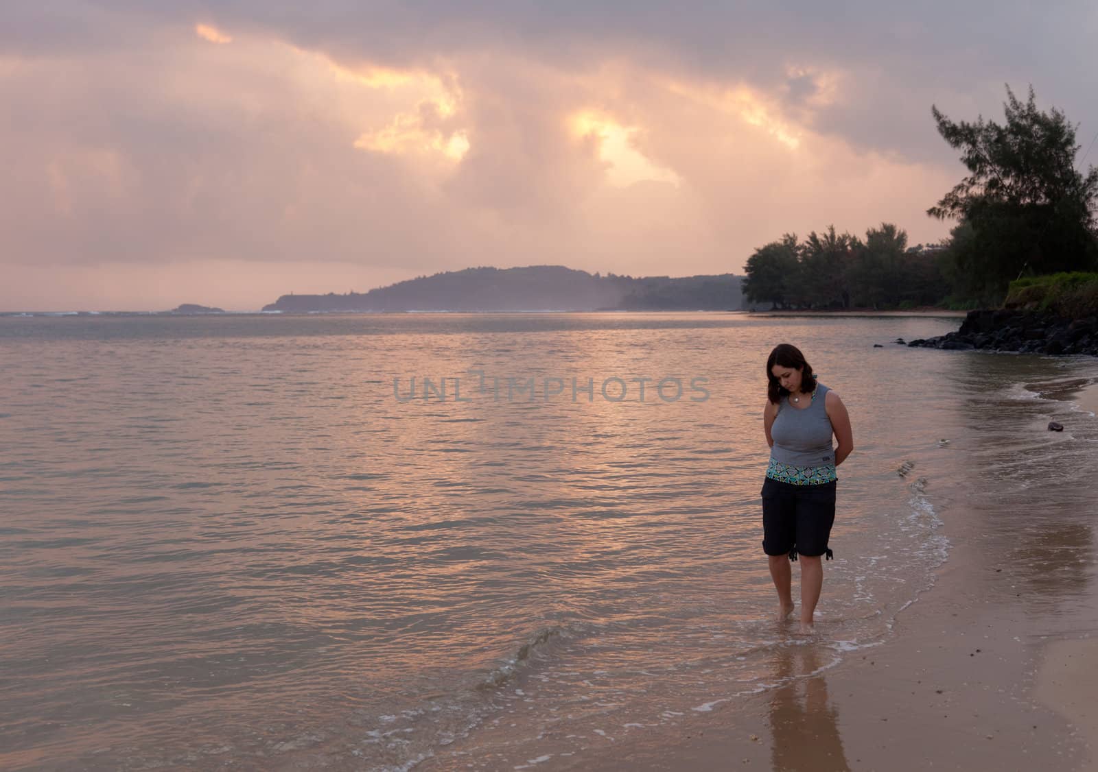 Girl paddling in ocean at sunrise on Anini beach
