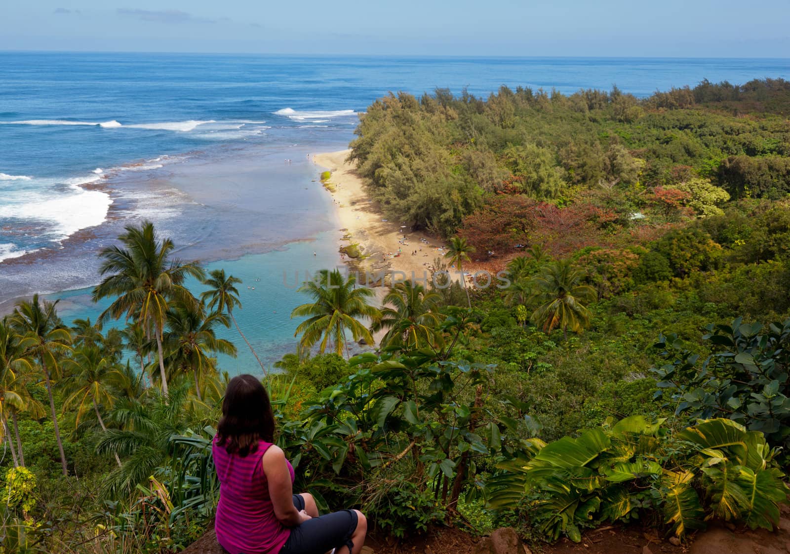 Female hiker overlooking Kee beach from Kalalau trail on Na Pali coast of Kauai