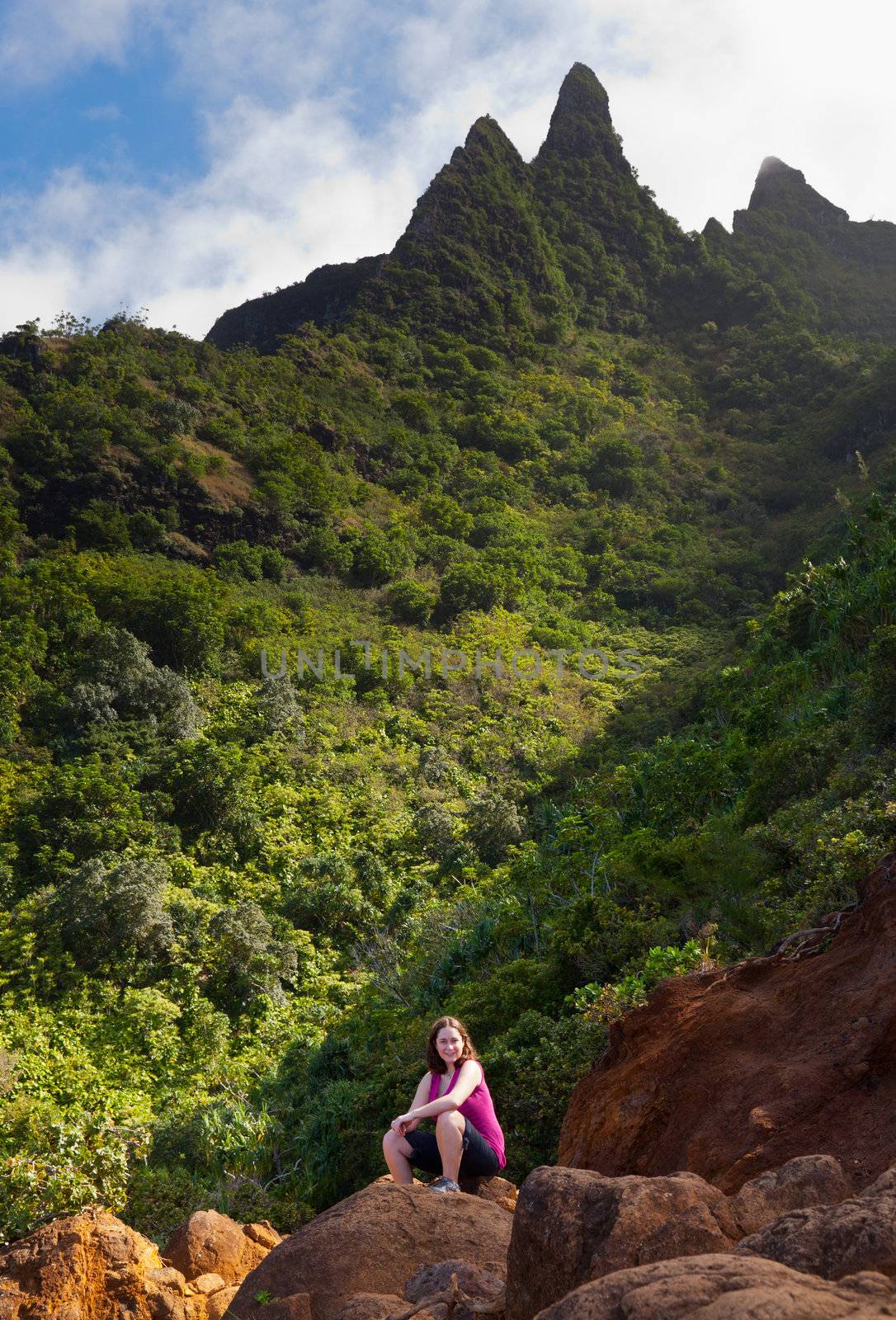 Single woman walker on rock on Kalalau trail along Na Pali coast in Kauai Hawaii