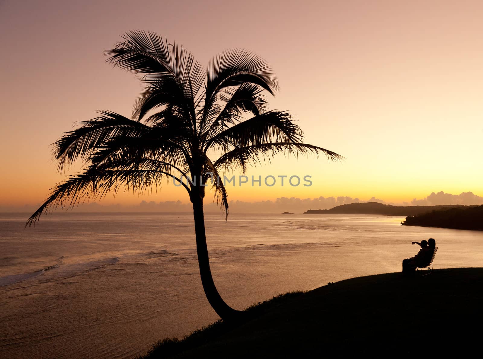 Sunrise with couple between two palm trees and looking towards Kilauea lighthouse