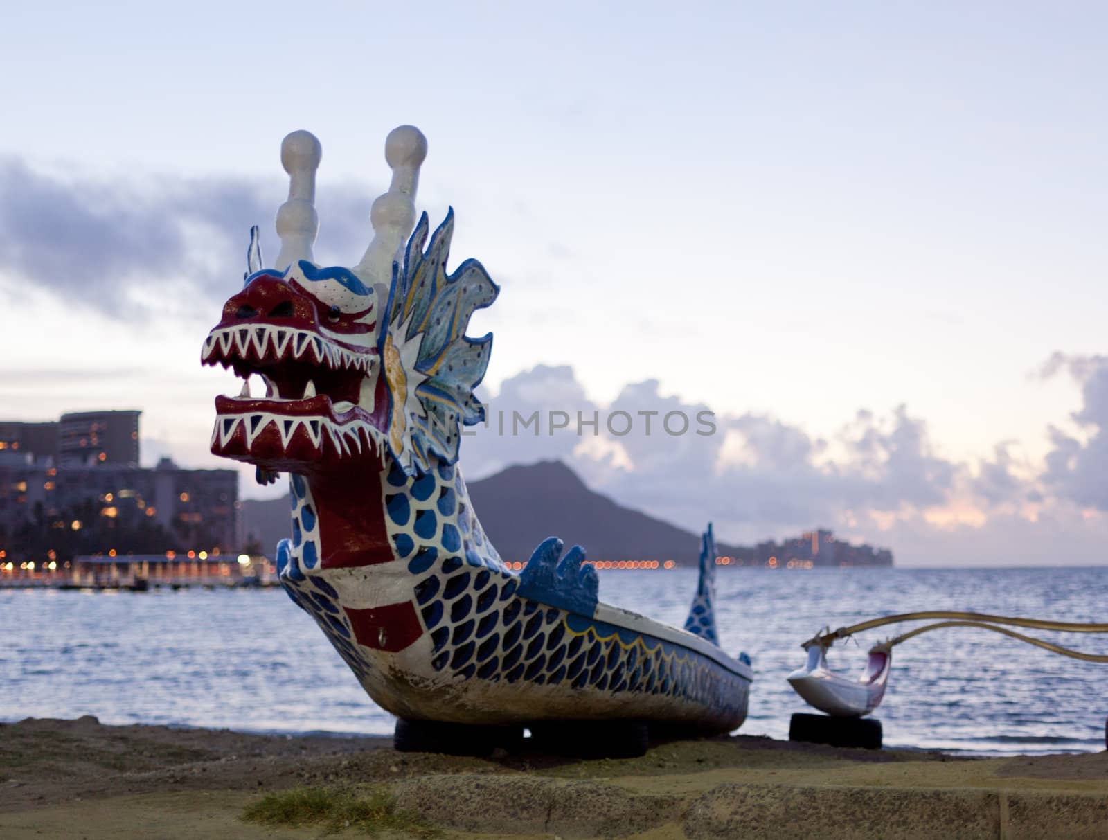 Dragon shaped head on traditional canoe on sand in Waikiki with Diamond Head