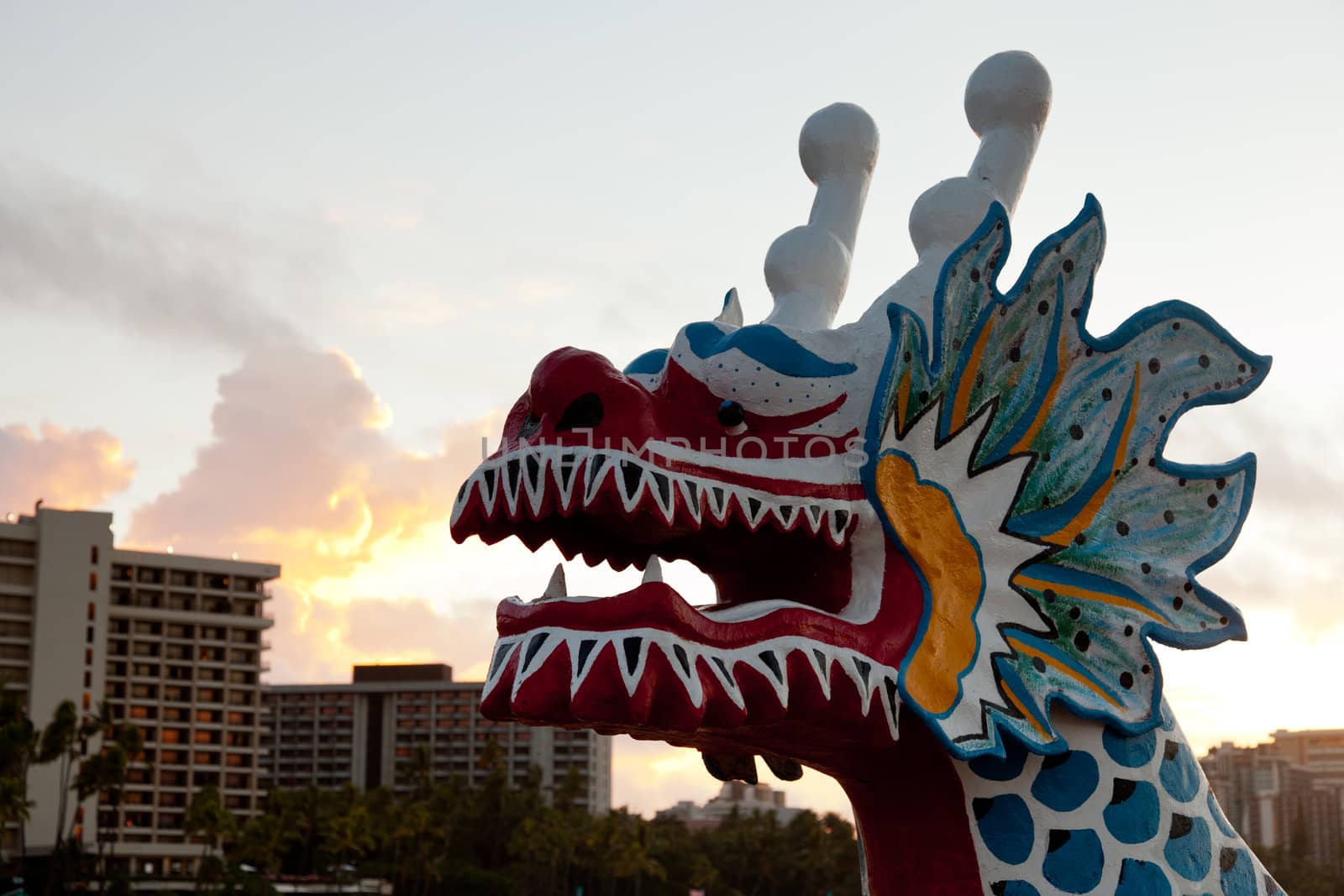 Dragon shaped head on traditional canoe on sand in Waikiki with hotels
