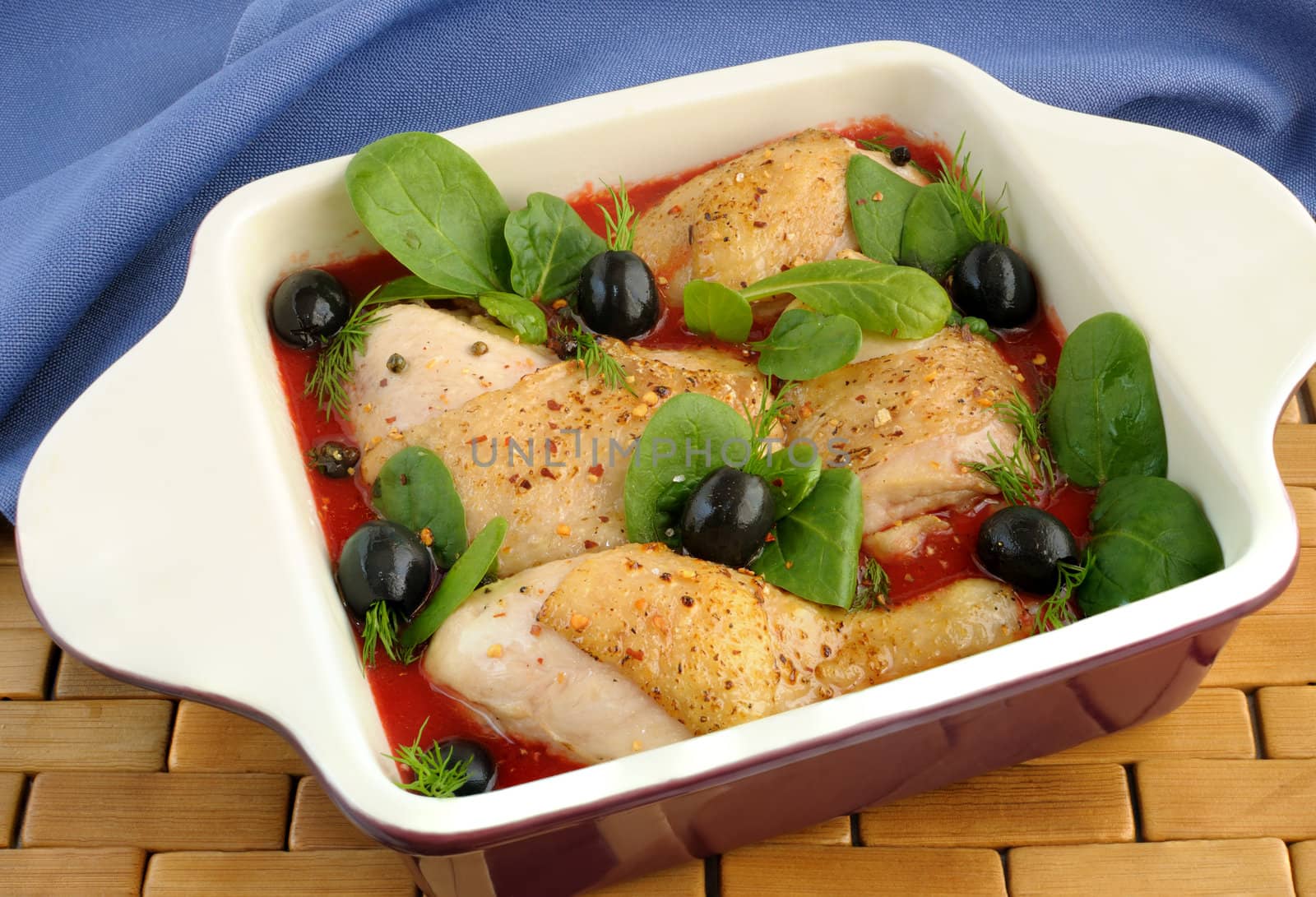 Pieces of chicken in tomato sauce with olives, spinach and spices