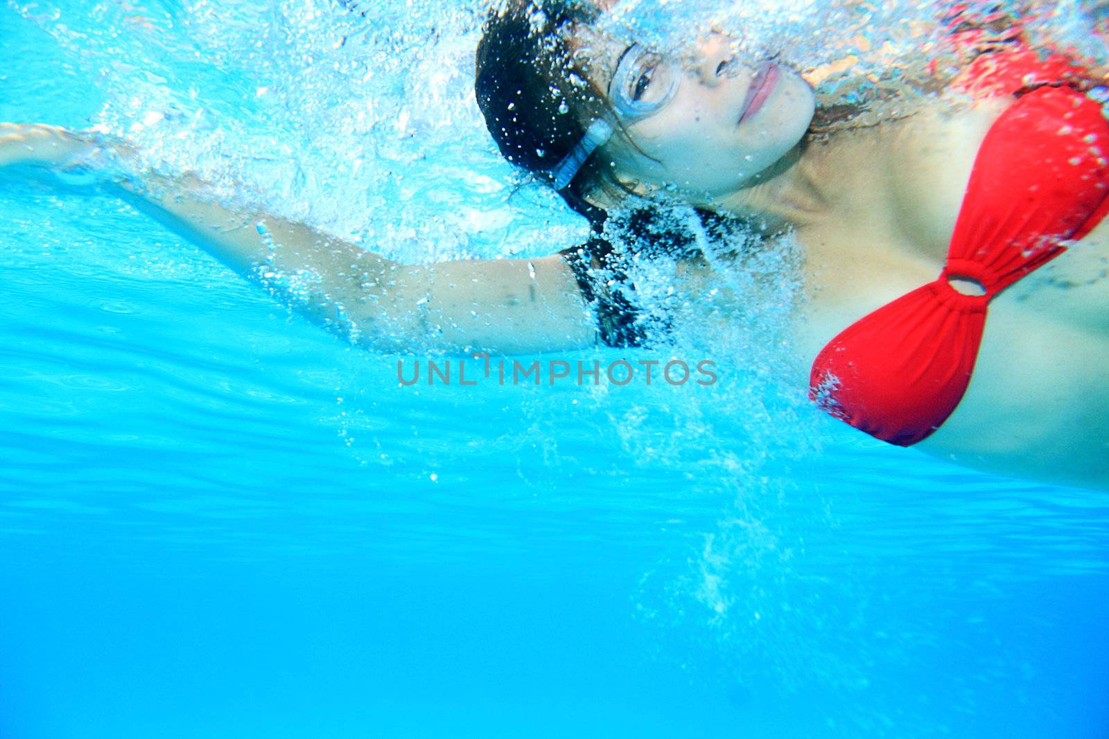 Swimming woman. Swimmer underwater image of girl swimming crawl in red bikini wearing swimming goggles.