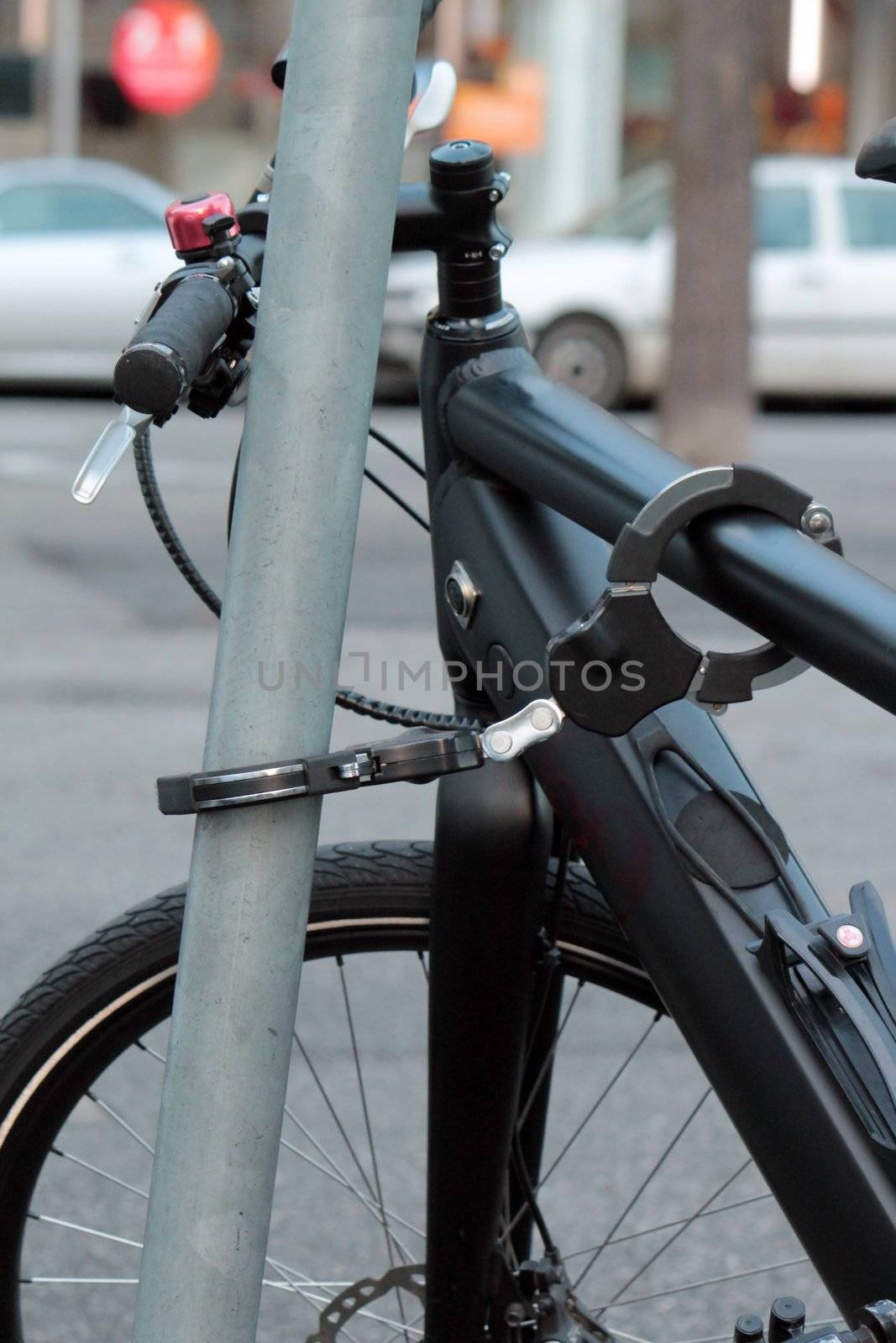 Black city bike hooked to a post with a padlock