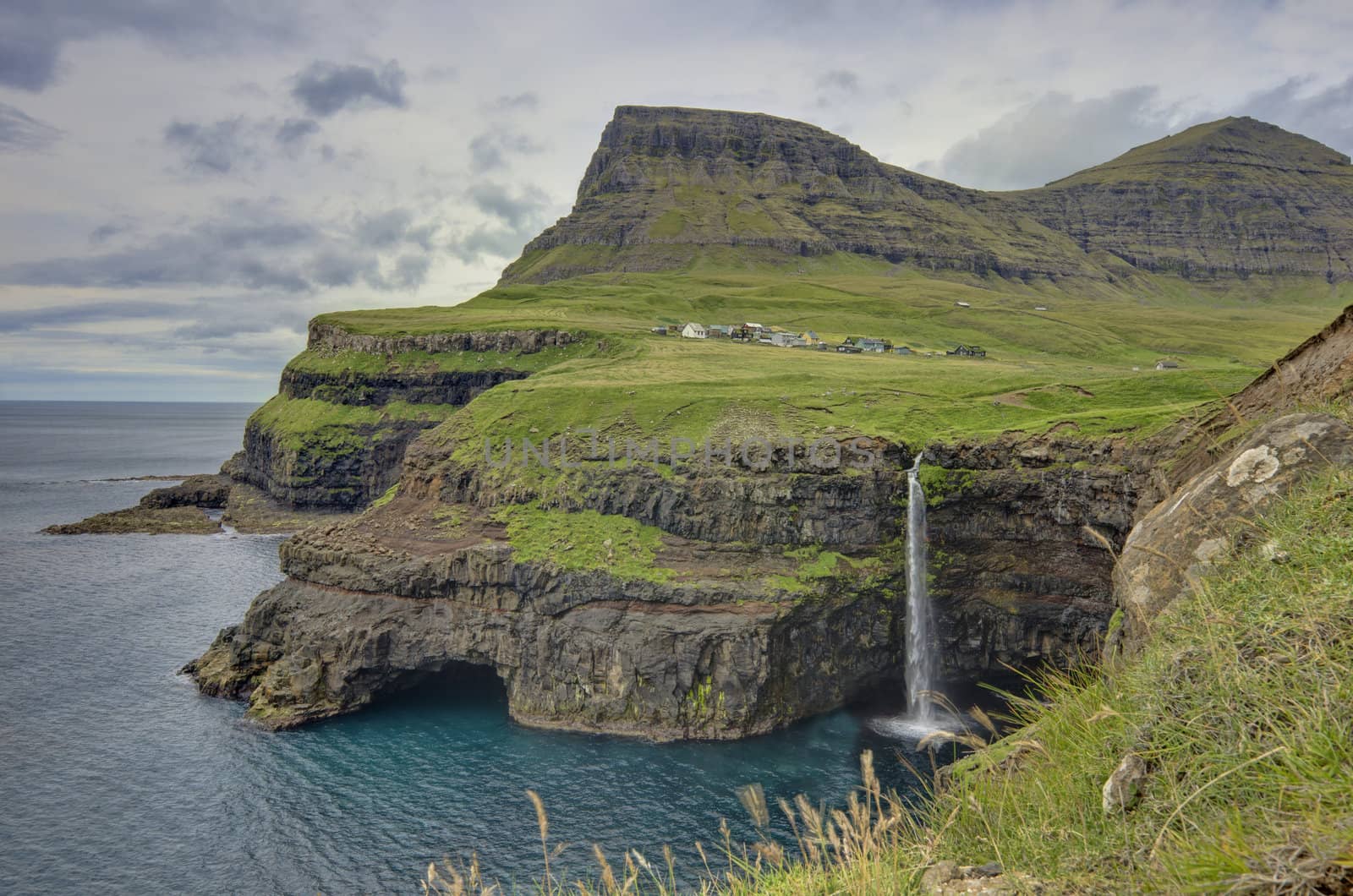 The village 'Gásadalur' is surrounded by high mountains and the clear blue Atlantic on the island 'Vagar'.