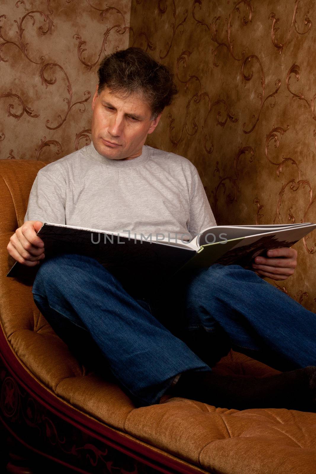 Portrait of middle-aged man reading a book in the black cover at home