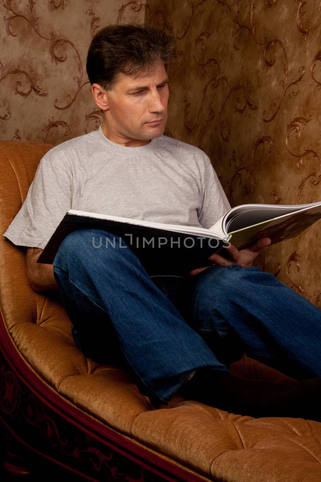 Portrait of middle-aged man reading a book in the black cover at home