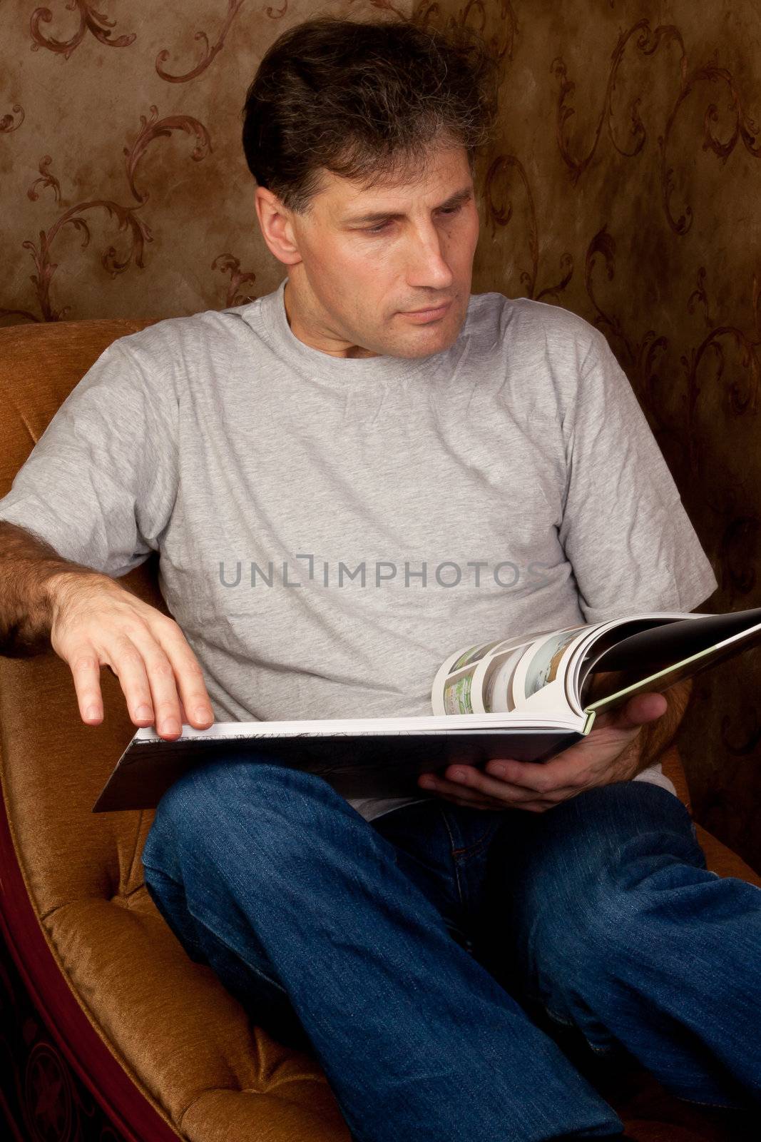 Portrait of middle-aged man reading a book in the black cover at home