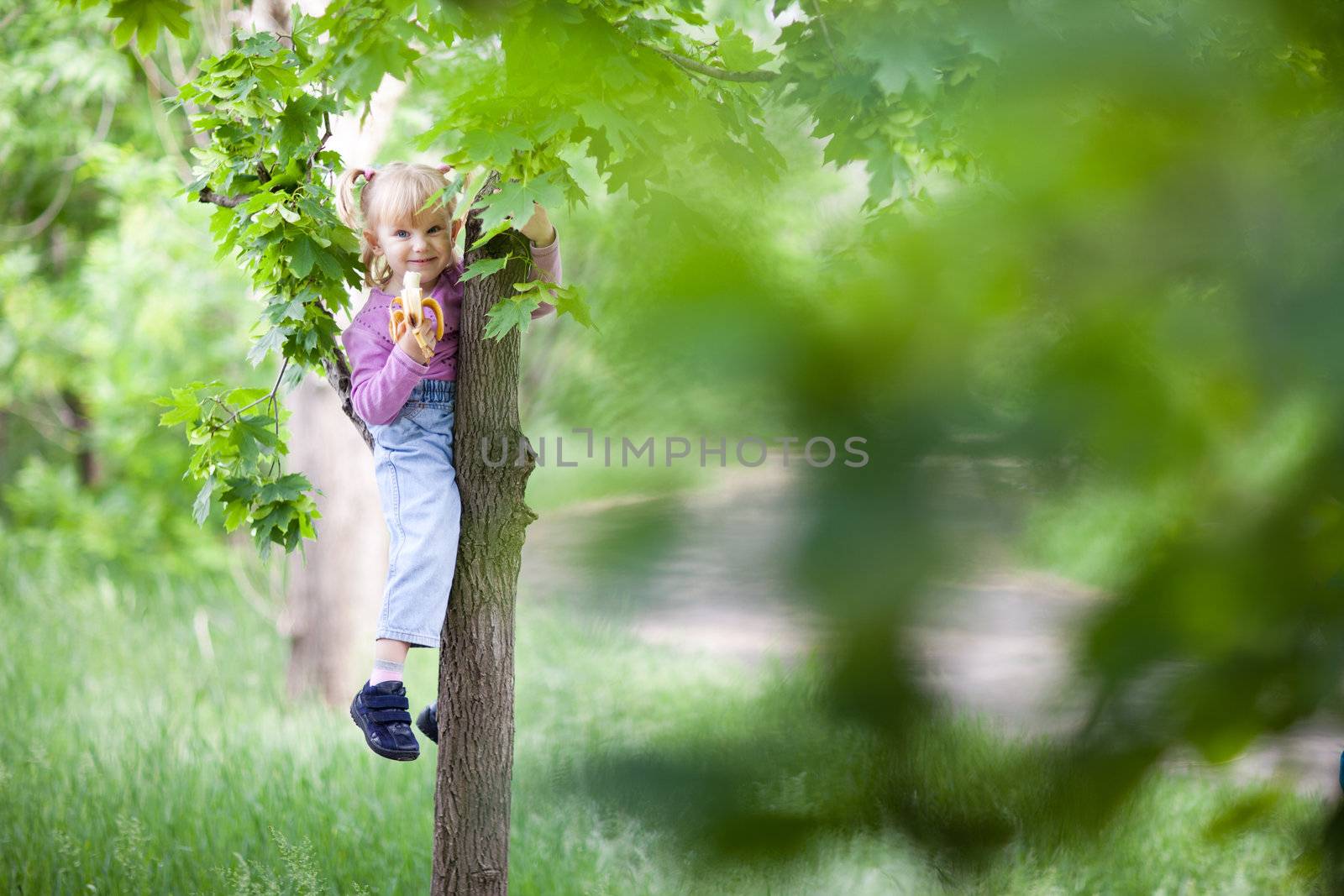 small girl eating banana on the tree