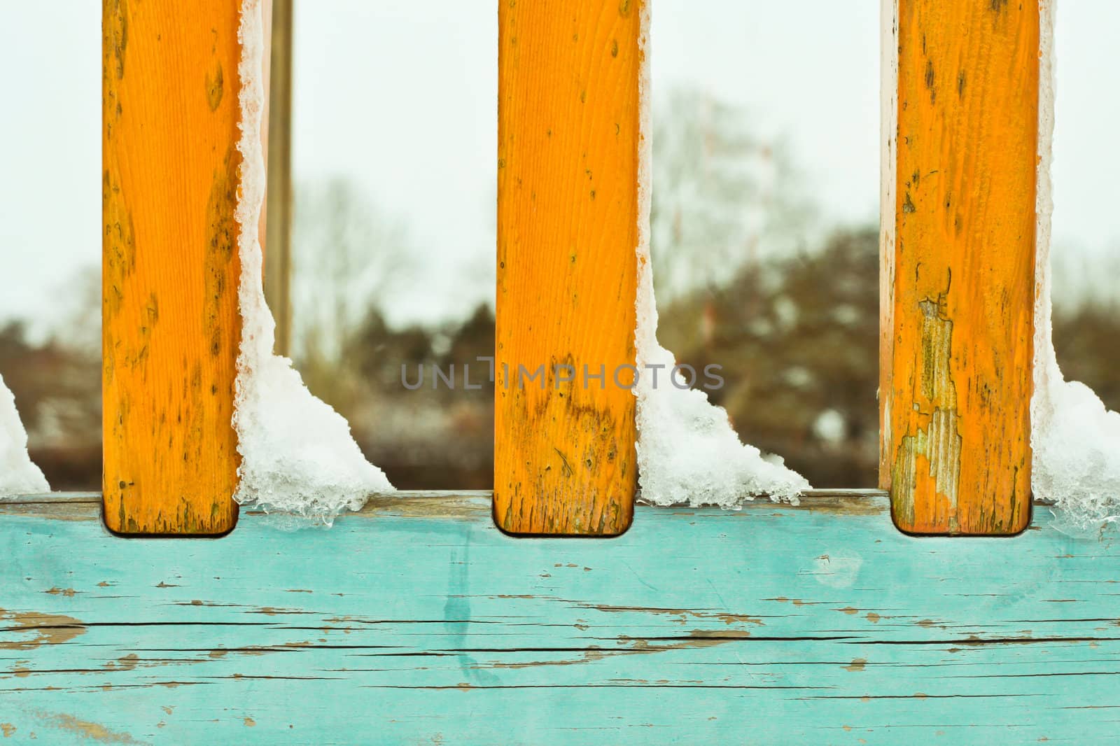 Snow clumps on a colorful wooden set of railings