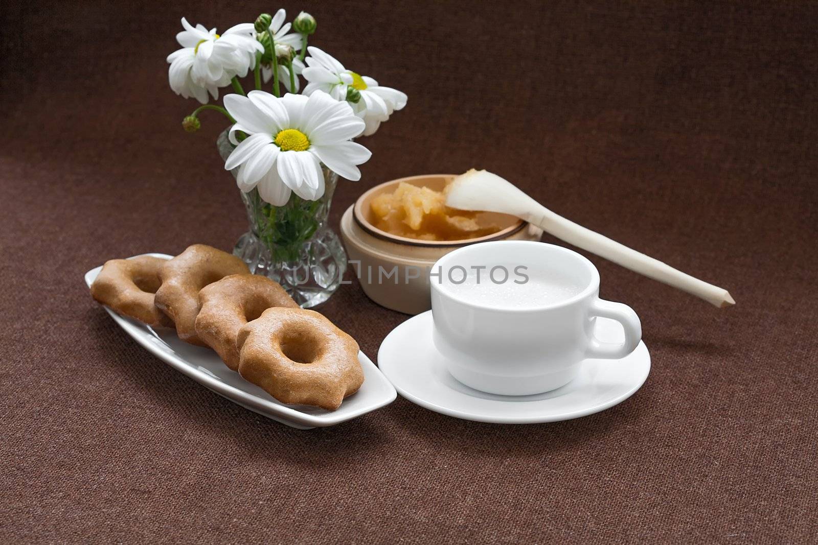 honey, cookies, and a vase of daisies on a fabric background