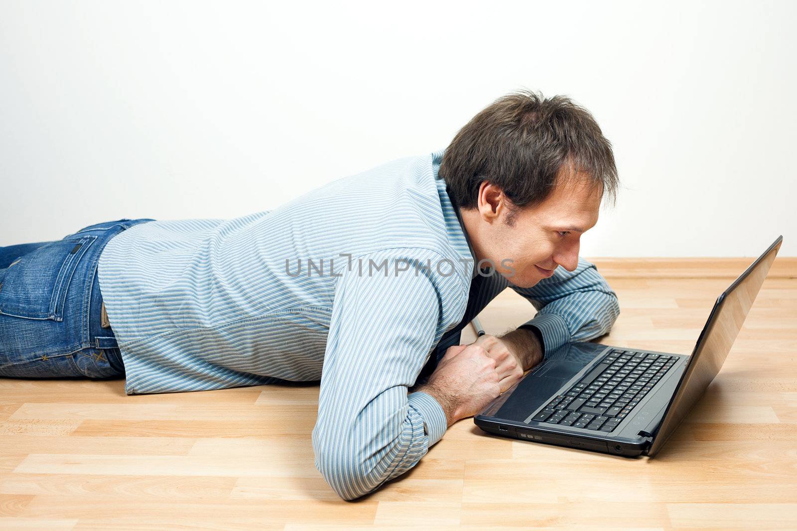 young man using laptop  lying on the floor in the room