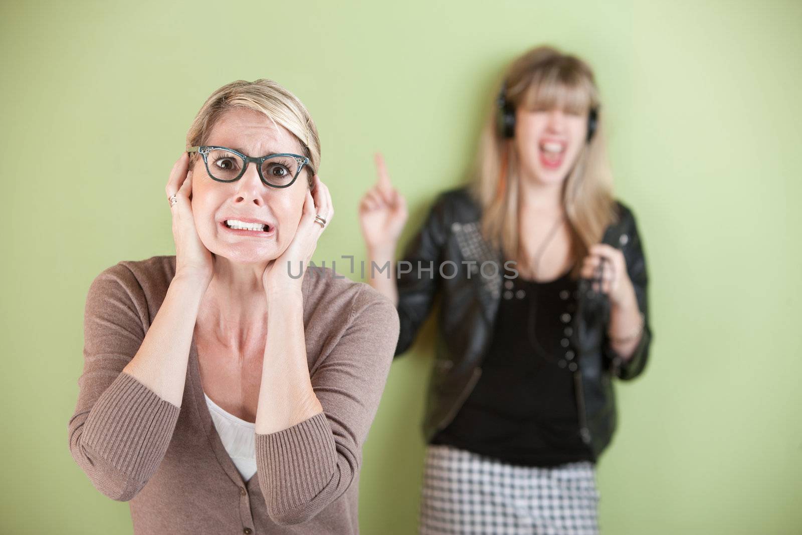 Woman with ears covered in front of loud teen