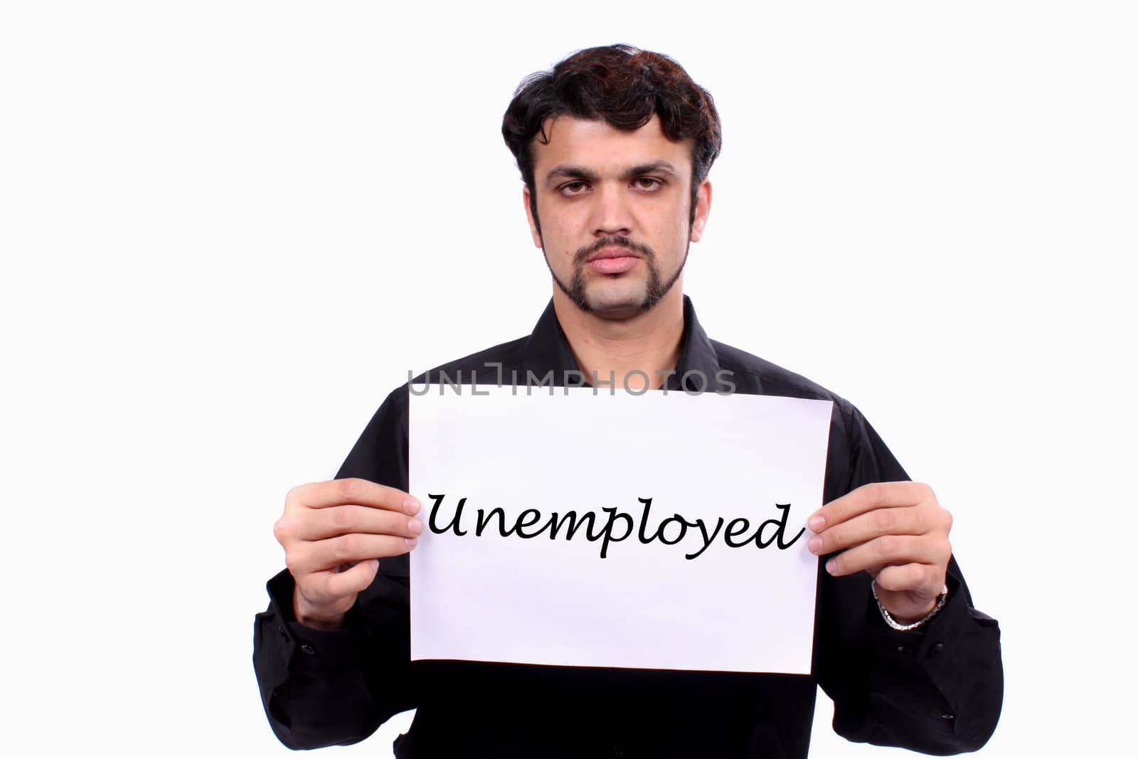 A sad unemployed Indian man holding an 'unemployment' sign, on white studio background.