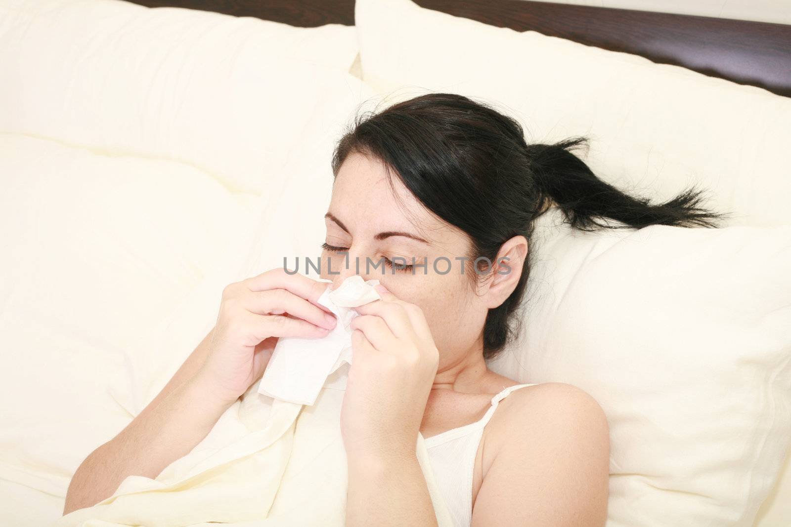 Closeup of gorgeous caucasian woman with cold sneezing into tissue over white background