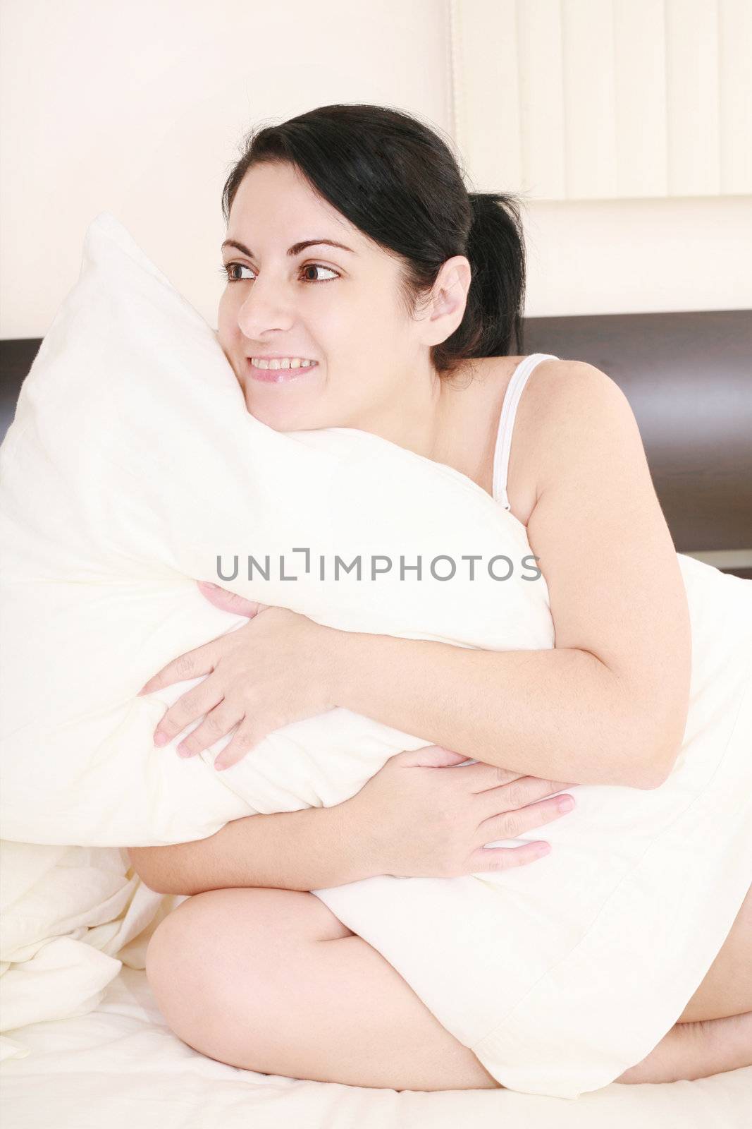 Young woman holding a pillow against a white background by dacasdo
