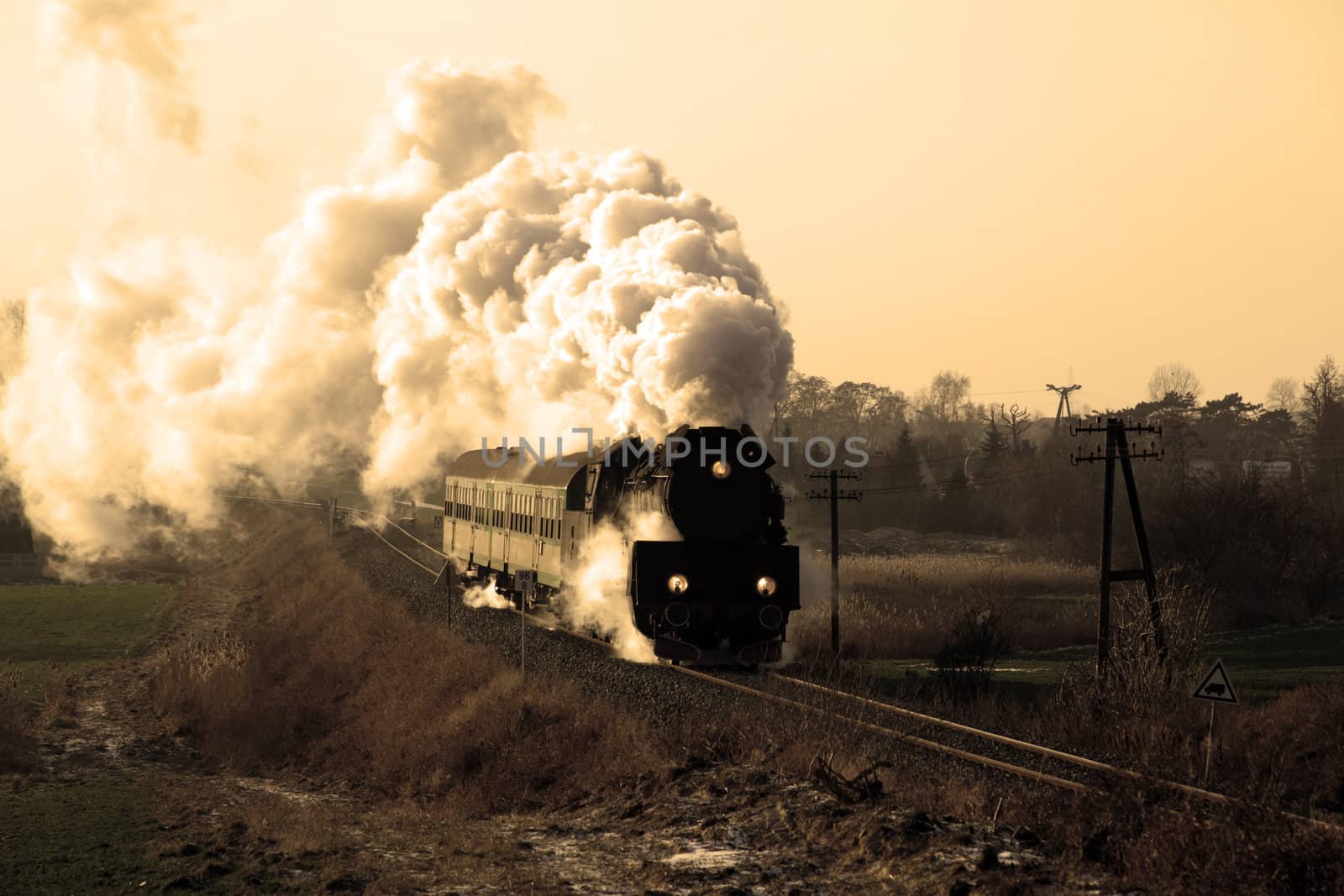 Vintage steam train passing through countryside, wintertime
