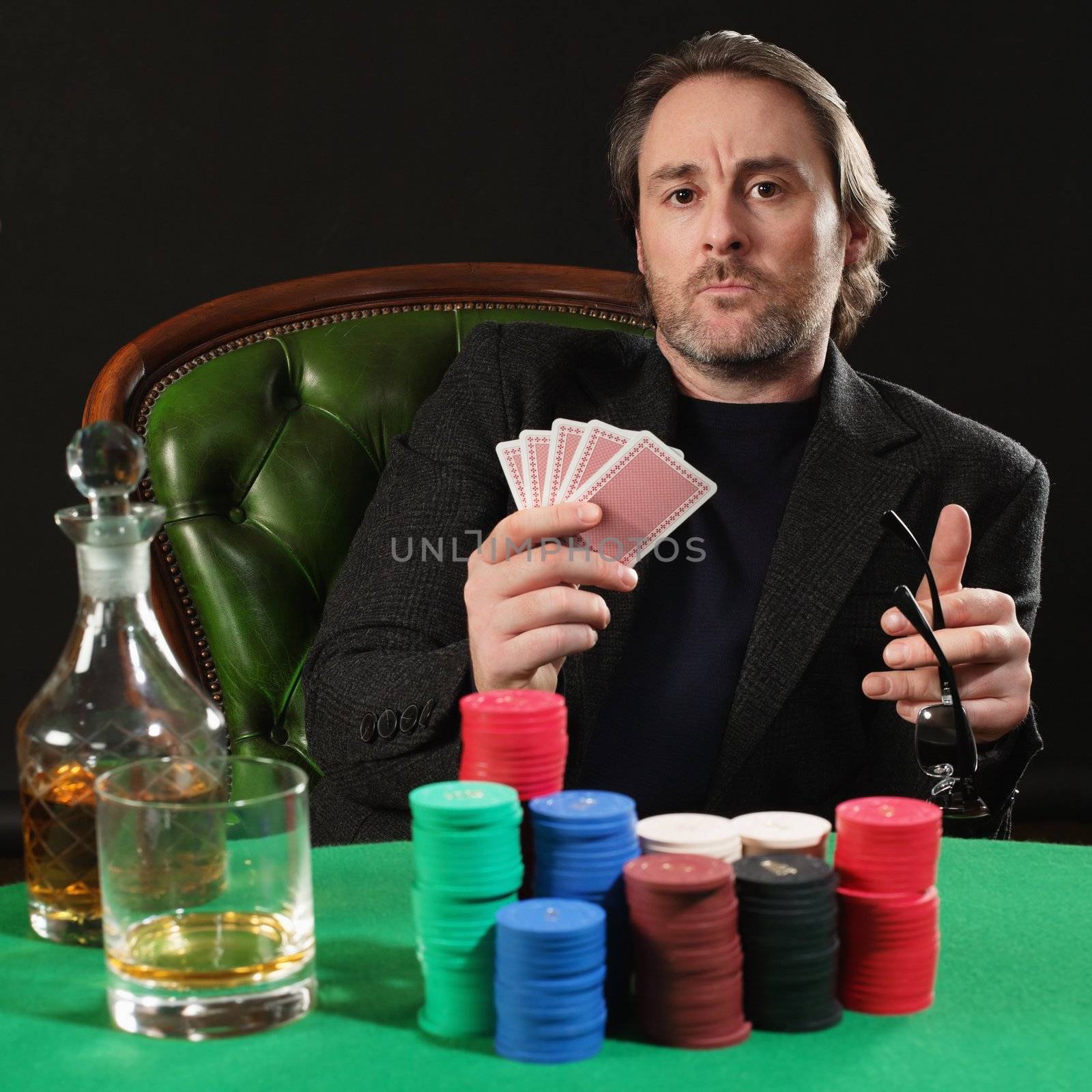 Photo of a professional poker player with a large stack of gambling chips. Playing cards have been altered to be generic.