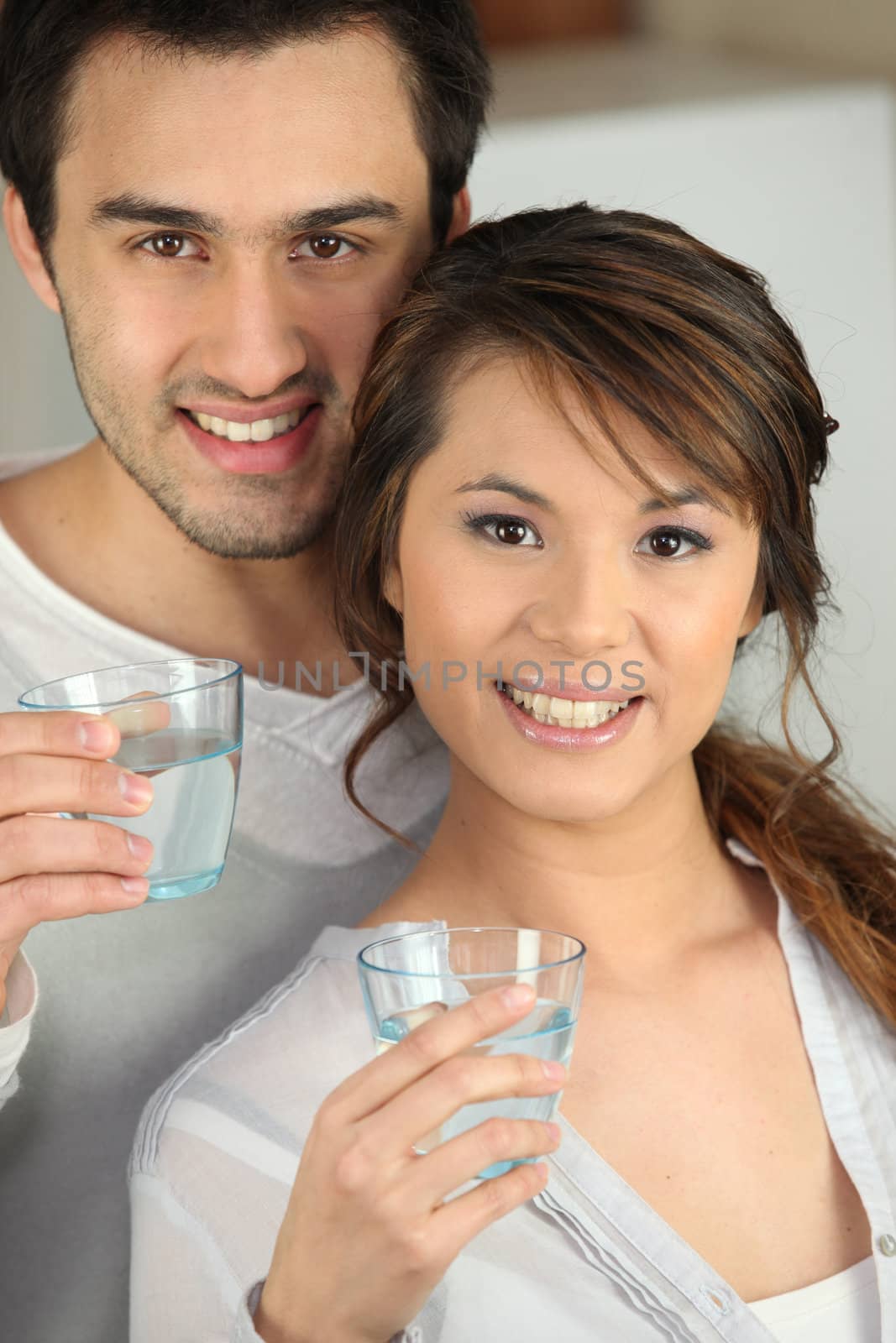 Enthusiastic man and woman with glasses of water by phovoir
