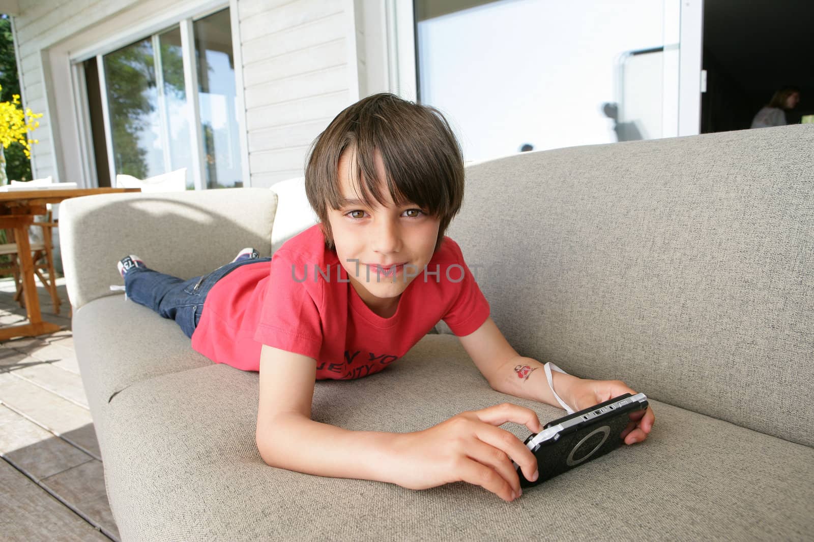 Little boy laying on sofa with hand-held video game